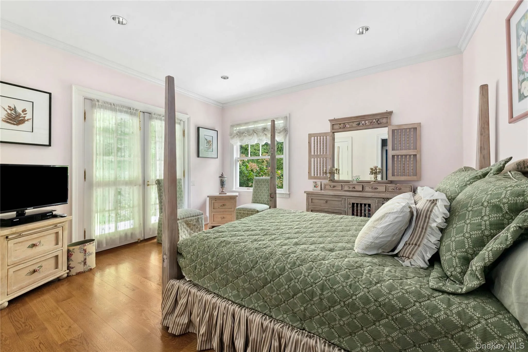 Bedroom featuring crown molding, wood finished floors, and access to exterior Bedroom featuring crown molding, wood finished floors, and access to exterior