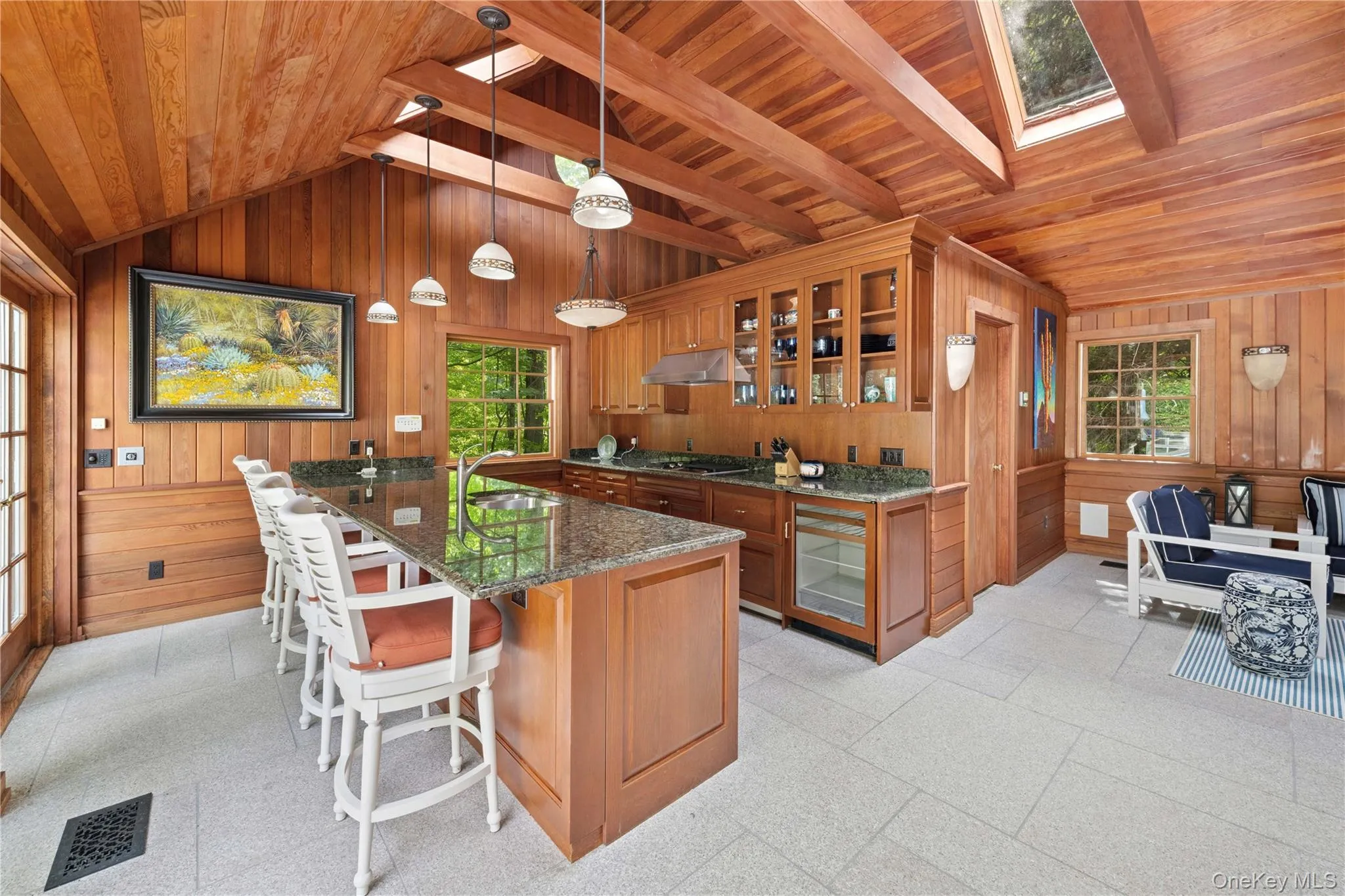 Kitchen with glass insert cabinets, a skylight, brown cabinetry, a breakfast bar, and wooden walls Kitchen with glass insert cabinets, a skylight, brown cabinetry, a breakfast bar, and wooden walls