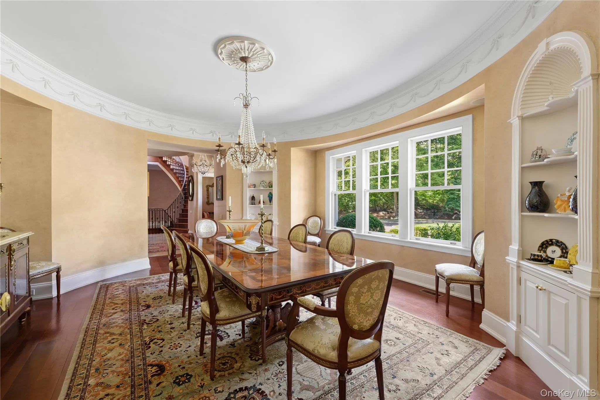 Dining space with built in shelves, dark wood-style floors, stairway, crown molding, and a chandelier Dining space with built in shelves, dark wood-style floors, stairway, crown molding, and a chandelier