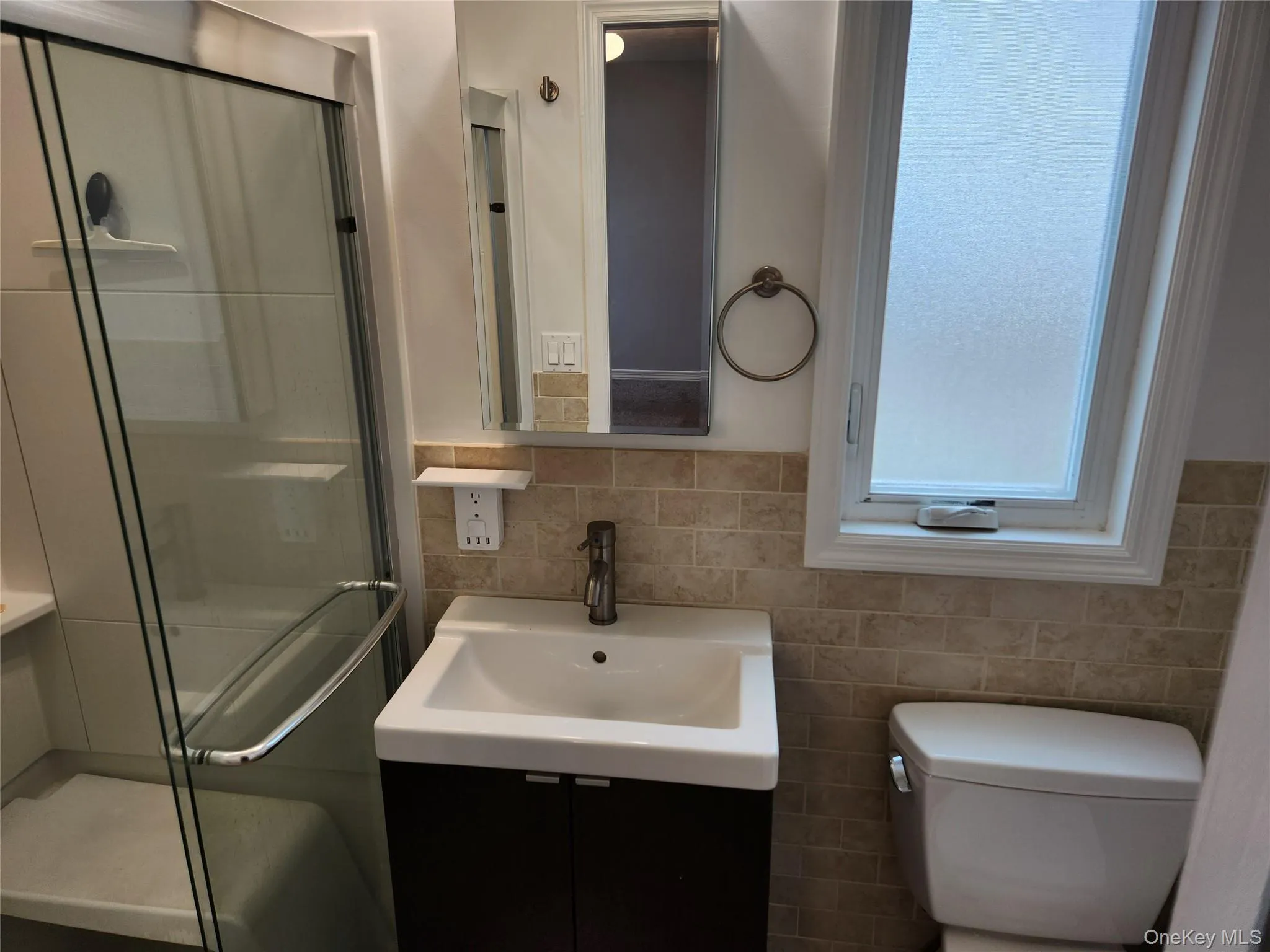 Bathroom with vanity, a stall shower, and tile walls Bathroom with vanity, a stall shower, and tile walls