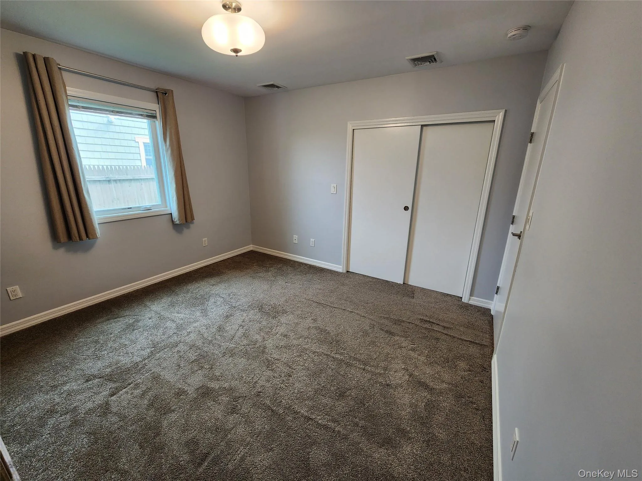 Unfurnished bedroom with dark carpet and a closet Unfurnished bedroom with dark carpet and a closet