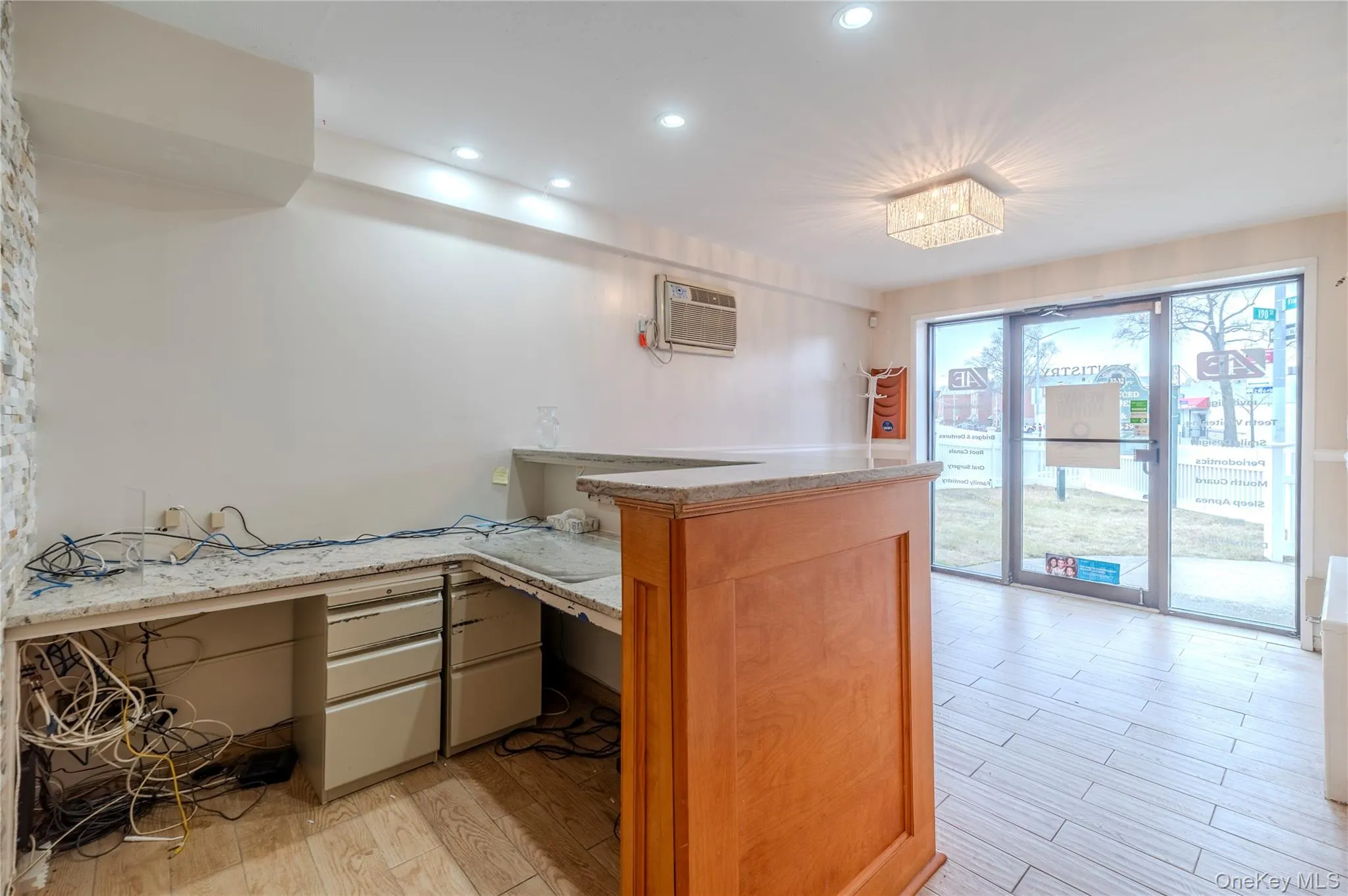 Kitchen featuring light wood-type flooring, light stone counters, recessed lighting, built in study area, and an AC wall unit Kitchen featuring light wood-type flooring, light stone counters, recessed lighting, built in study area, and an AC wall unit