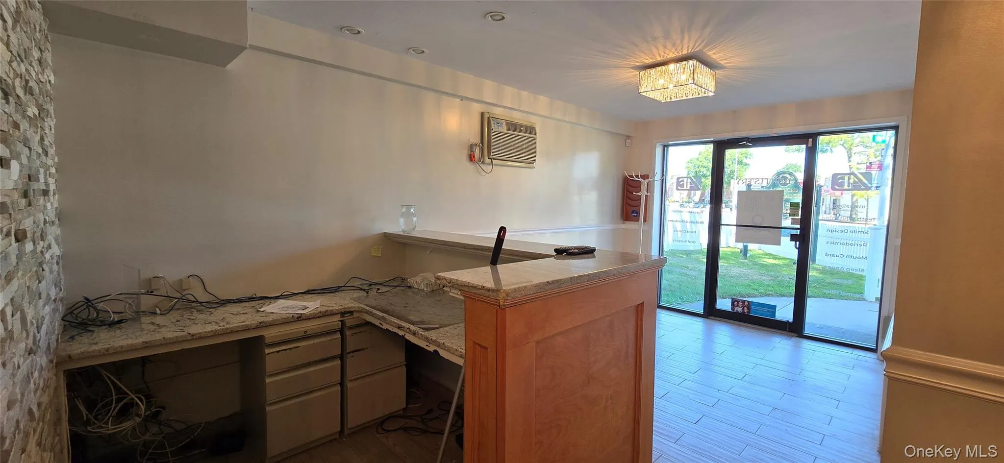 Kitchen with a peninsula, an AC wall unit, wood finished floors, and light stone counters Kitchen with a peninsula, an AC wall unit, wood finished floors, and light stone counters