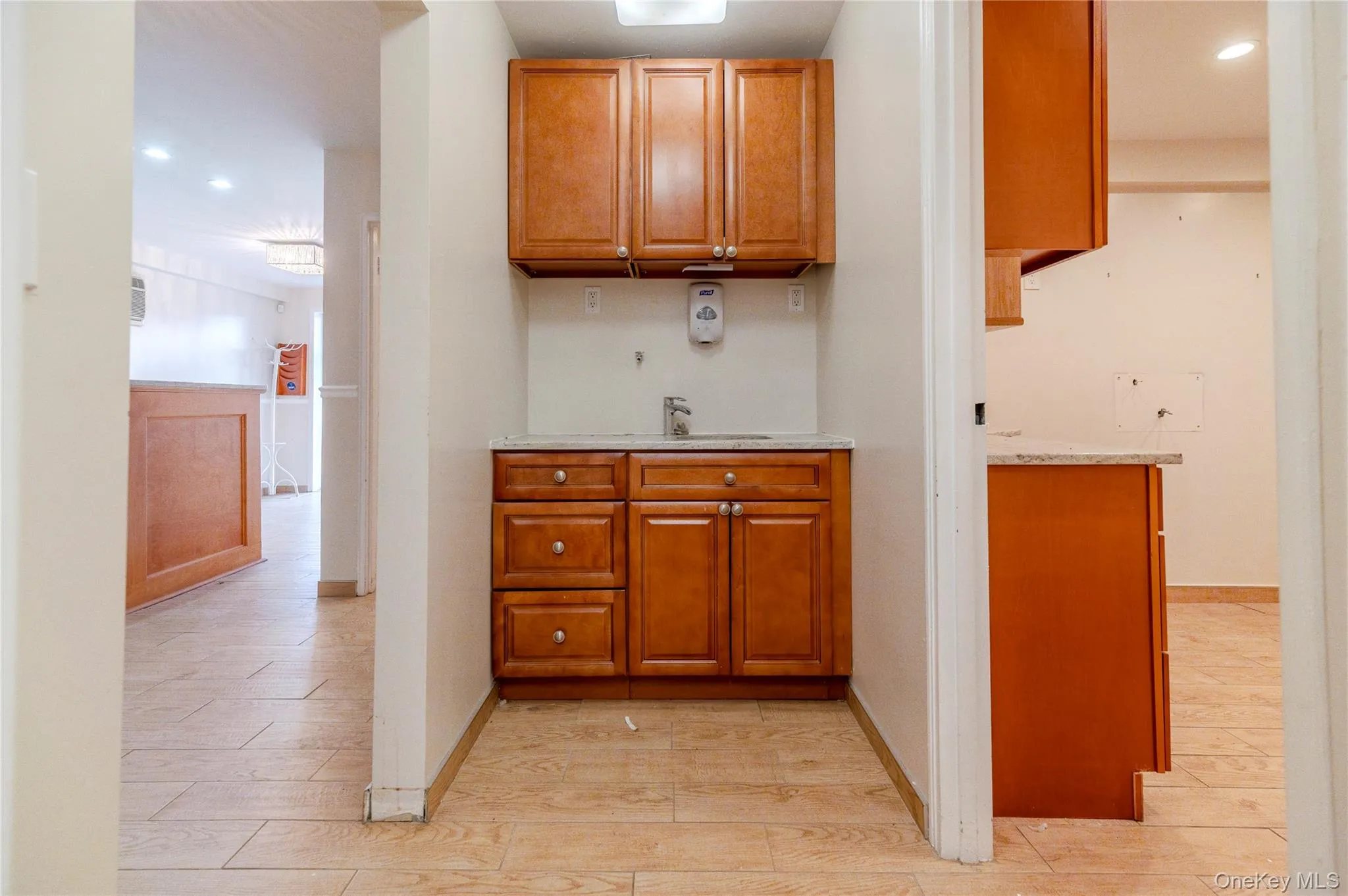 Bar with recessed lighting, brown cabinets, wood tiled floors, and light stone counters Bar with recessed lighting, brown cabinets, wood tiled floors, and light stone counters