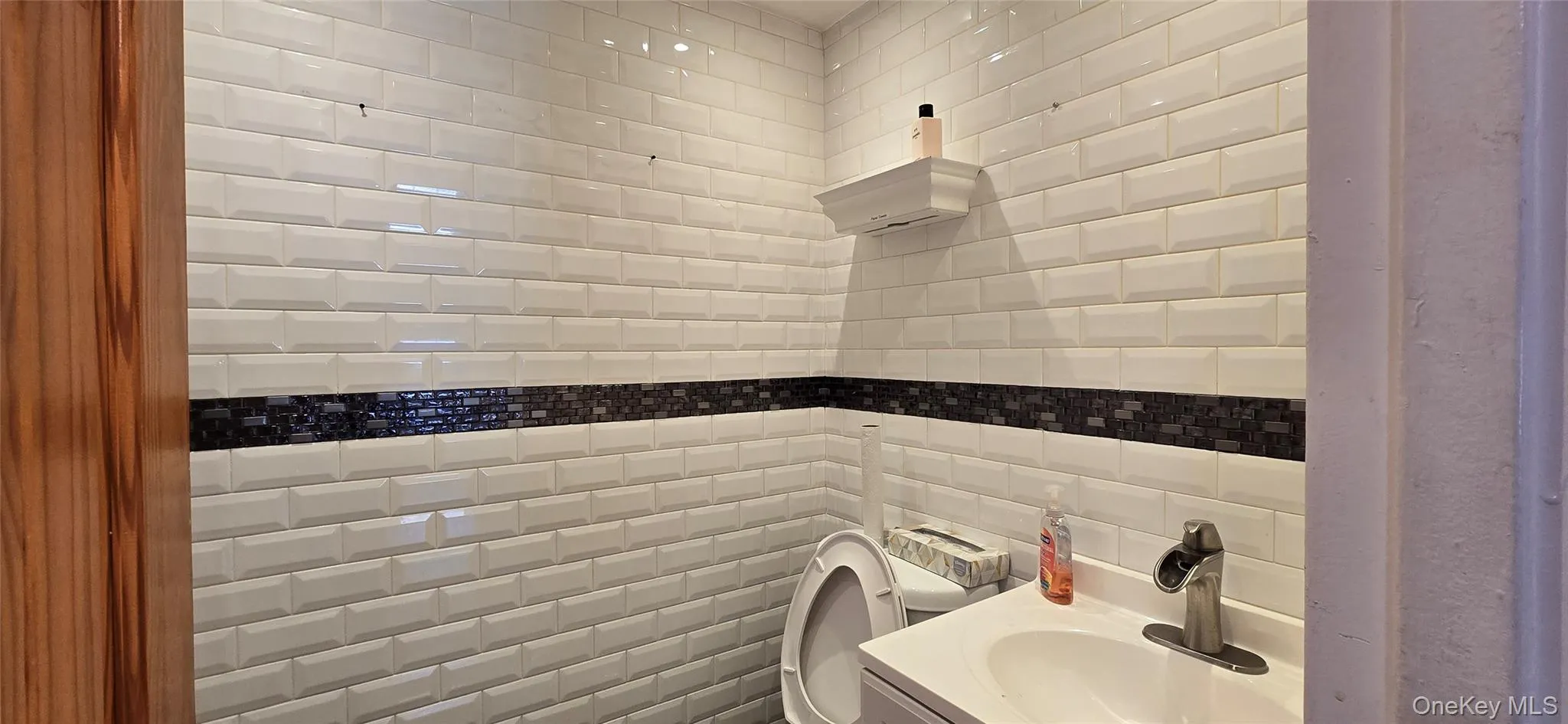 Half bathroom featuring tile walls, vanity, and decorative backsplash Half bathroom featuring tile walls, vanity, and decorative backsplash
