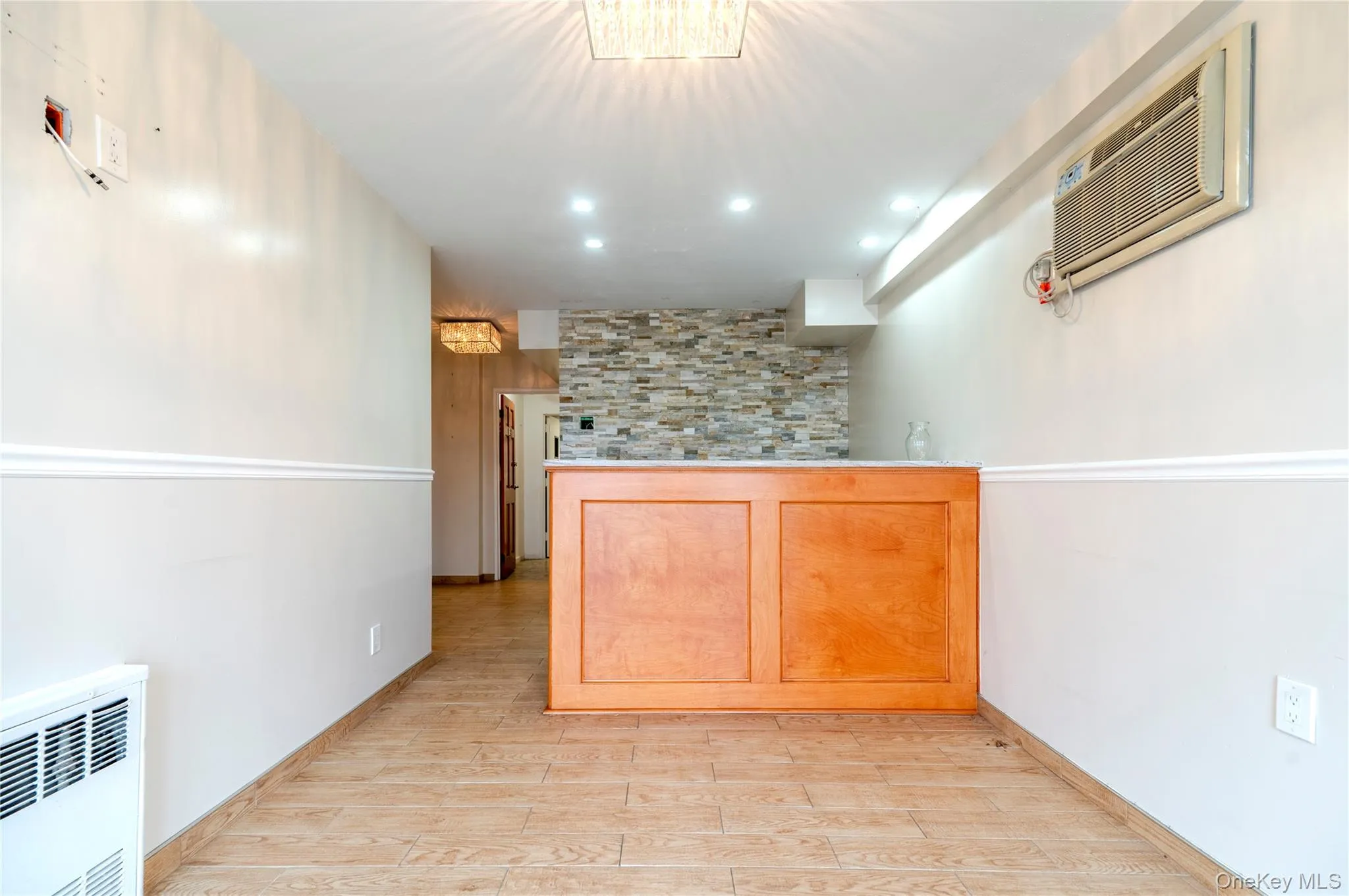 Bar featuring light wood-style flooring, radiator heating unit, a wall mounted AC, and recessed lighting Bar featuring light wood-style flooring, radiator heating unit, a wall mounted AC, and recessed lighting