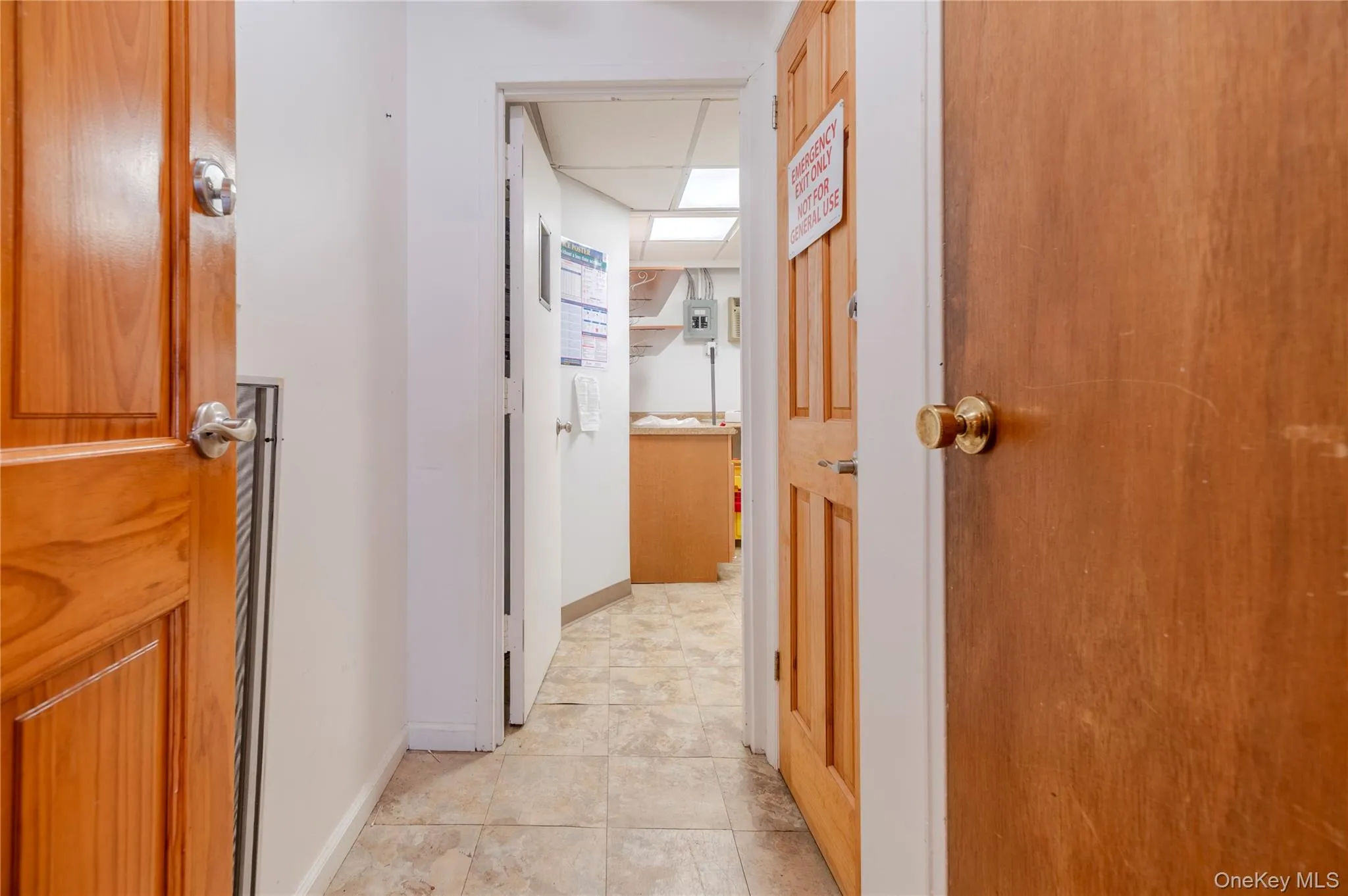 Corridor featuring light tile patterned floors and baseboards Corridor featuring light tile patterned floors and baseboards