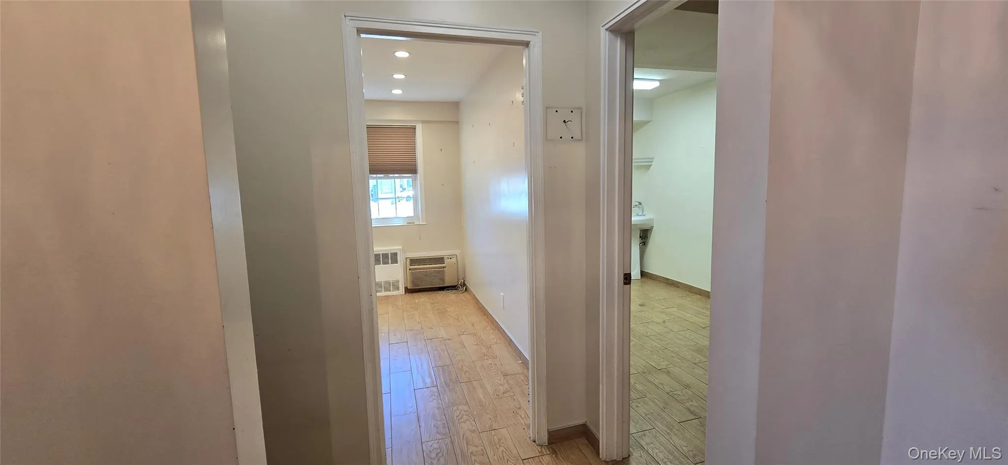 Hallway featuring light wood-type flooring, radiator heating unit, and recessed lighting Hallway featuring light wood-type flooring, radiator heating unit, and recessed lighting
