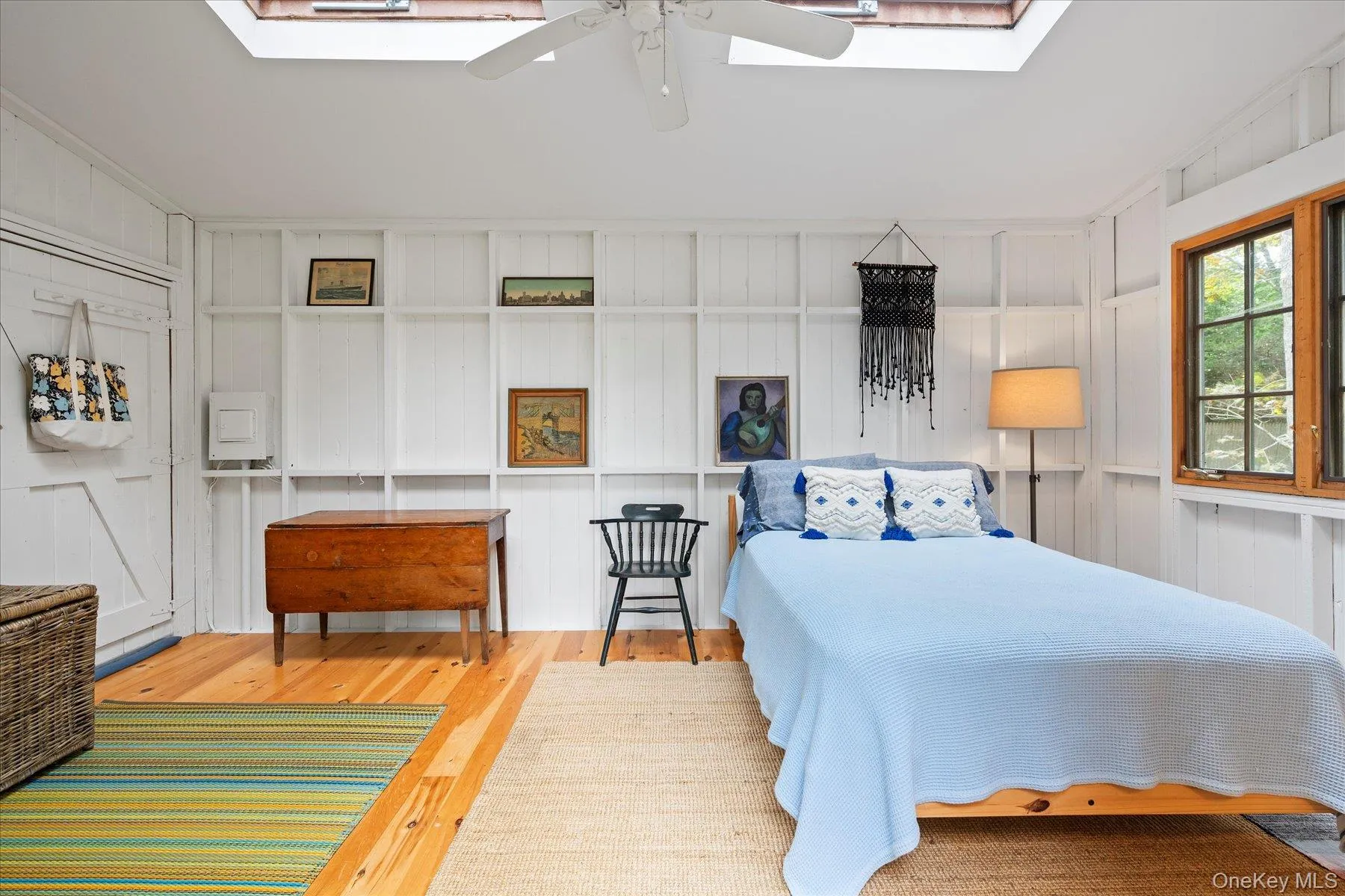 Bedroom featuring a skylight, wood finished floors, ceiling fan, and wooden walls