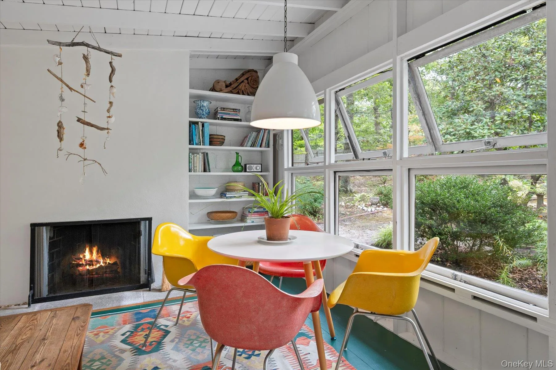Dining area featuring a warm lit fireplace and a wooden ceiling with exposed beams