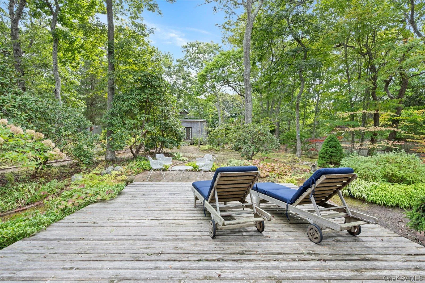 Wooden terrace with view of wooded area and a patio