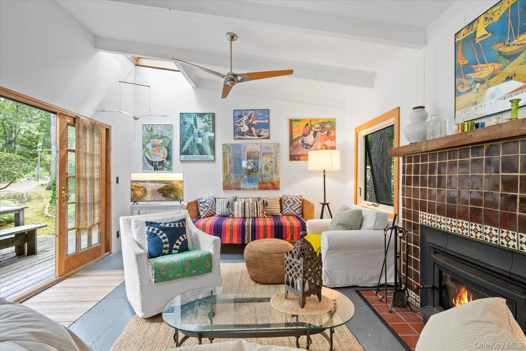 Tiled living area featuring plenty of natural light, a fireplace, a ceiling fan, and a skylight