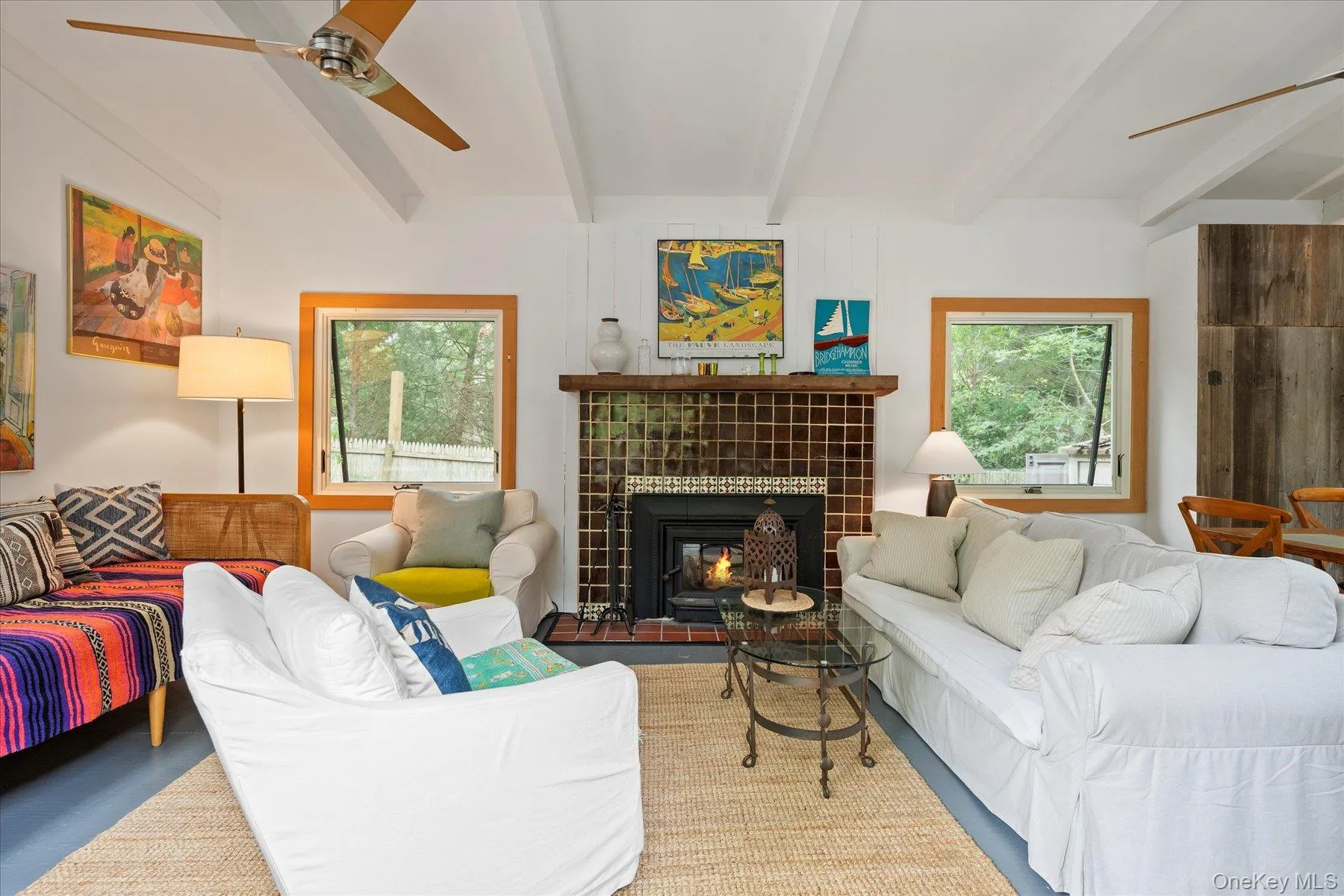Living area with ceiling fan, beam ceiling, plenty of natural light, and a tile fireplace