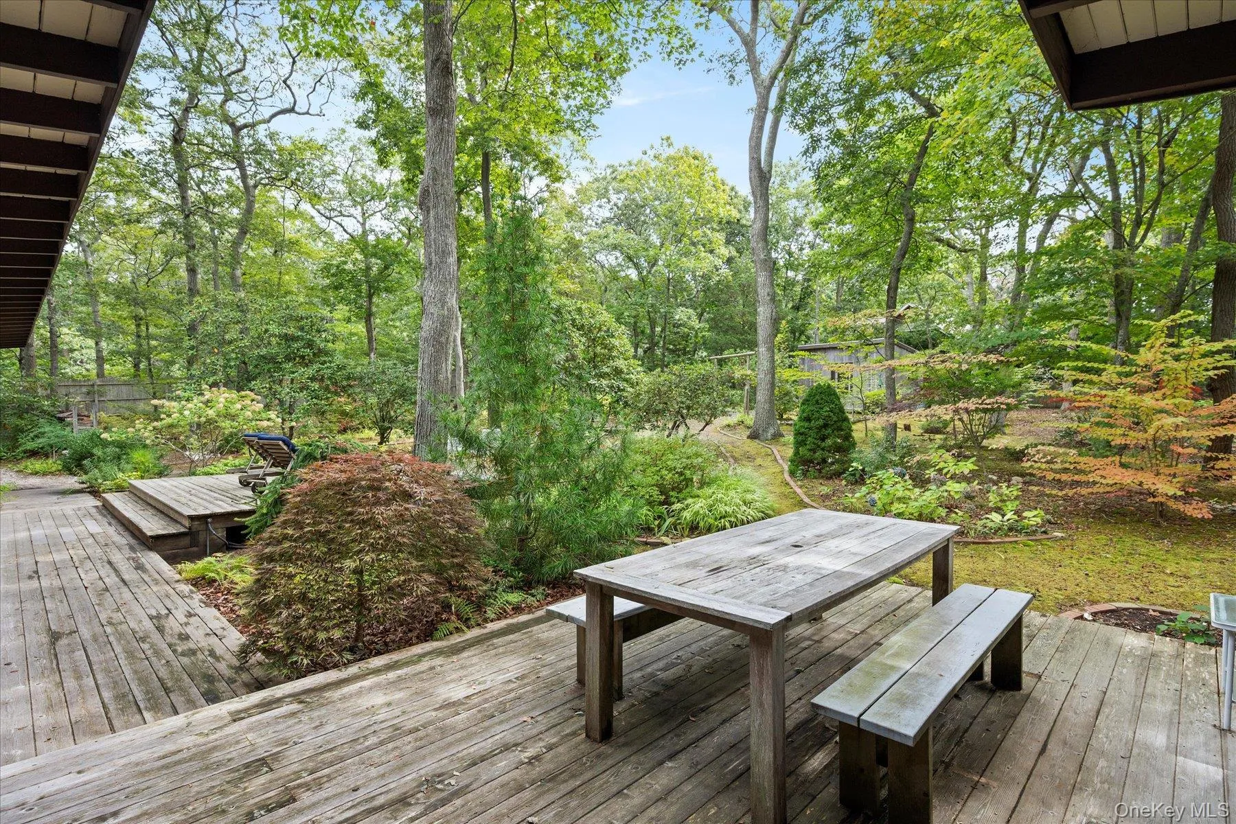 Wooden terrace featuring outdoor dining space and view of scattered trees