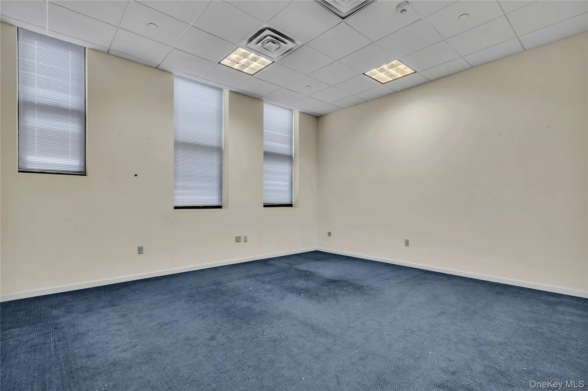 Unfurnished room with dark carpet and a drop ceiling Unfurnished room with dark carpet and a drop ceiling