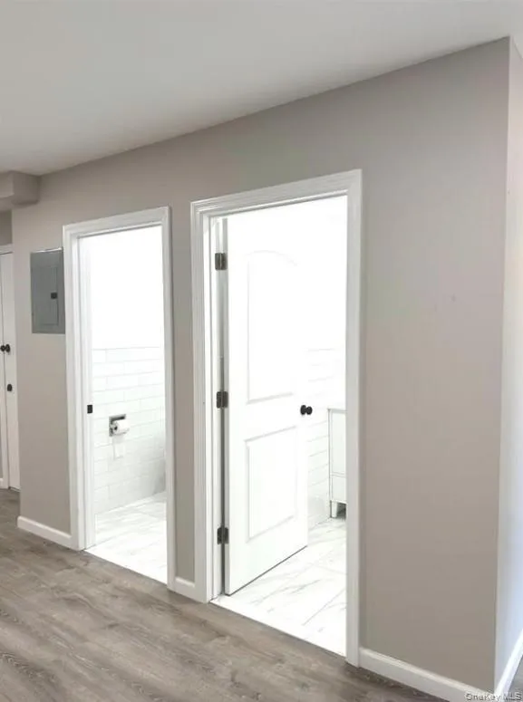 Corridor with light wood-style floors and electric panel Corridor with light wood-style floors and electric panel