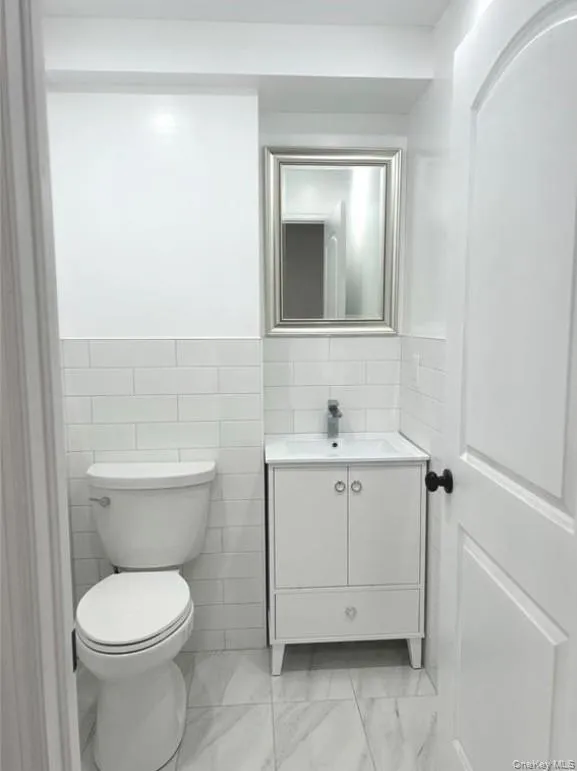 Bathroom with vanity, tile walls, and light marble finish flooring Bathroom with vanity, tile walls, and light marble finish flooring