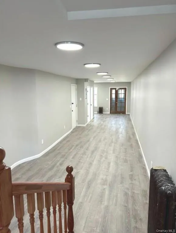 Hallway featuring radiator heating unit, wood finished floors, and french doors Hallway featuring radiator heating unit, wood finished floors, and french doors