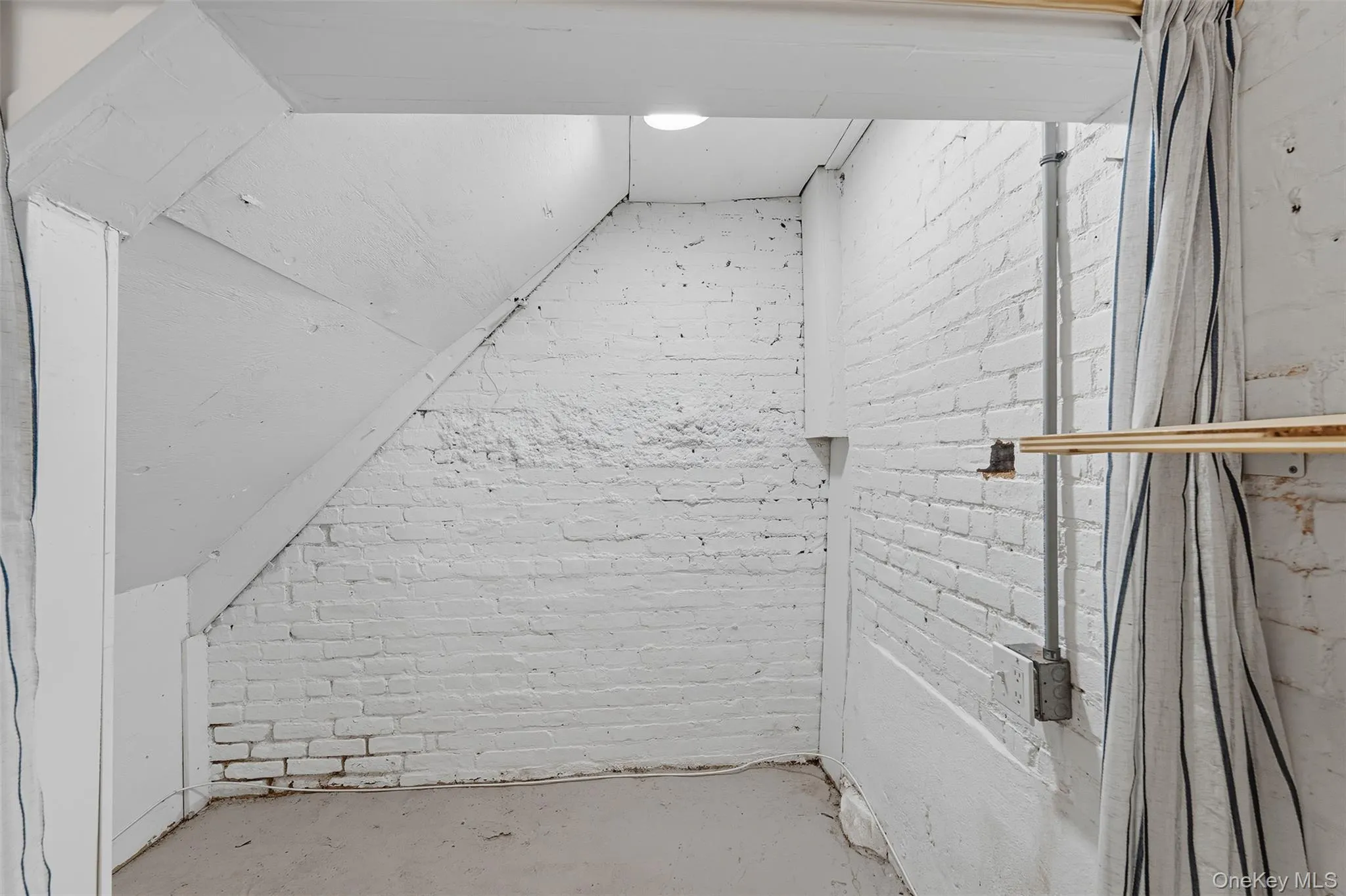 Bonus room with brick wall, concrete flooring, and vaulted ceiling Bonus room with brick wall, concrete flooring, and vaulted ceiling