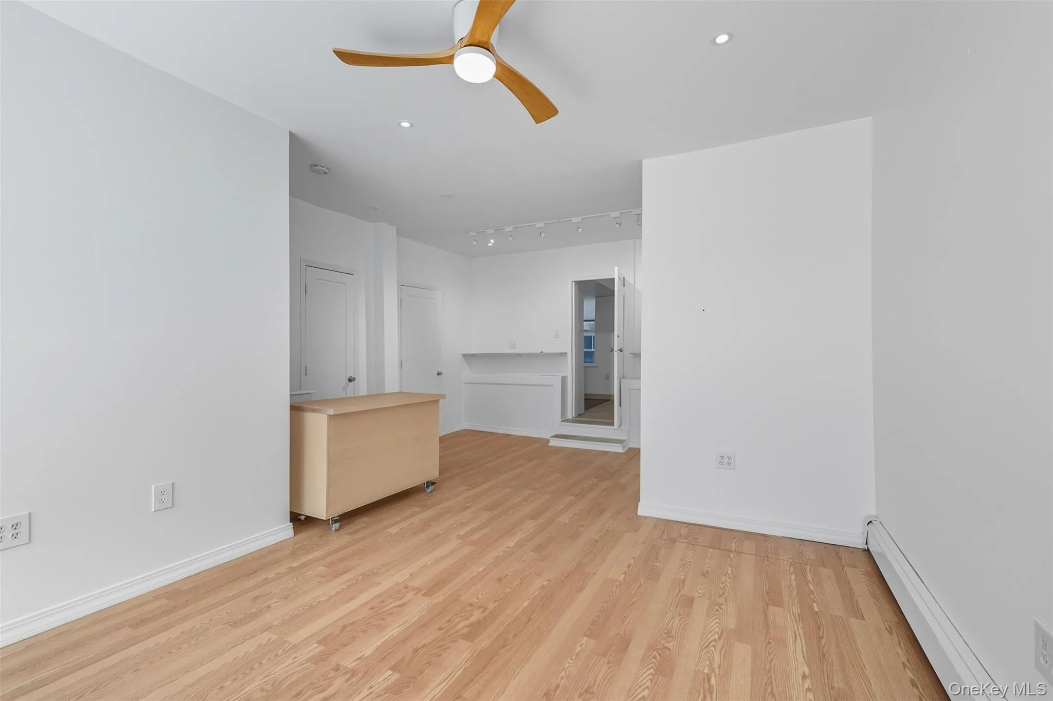 Unfurnished room with a baseboard radiator, light wood-style floors, a ceiling fan, track lighting, and recessed lighting Unfurnished room with a baseboard radiator, light wood-style floors, a ceiling fan, track lighting, and recessed lighting
