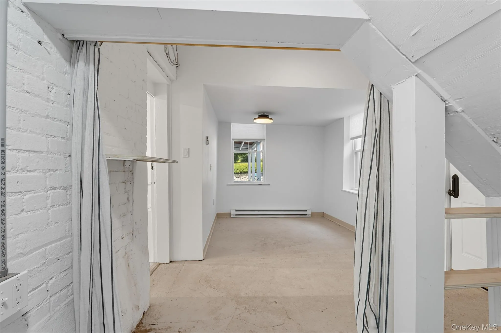 Hall with unfinished concrete flooring and a baseboard heating unit Hall with unfinished concrete flooring and a baseboard heating unit