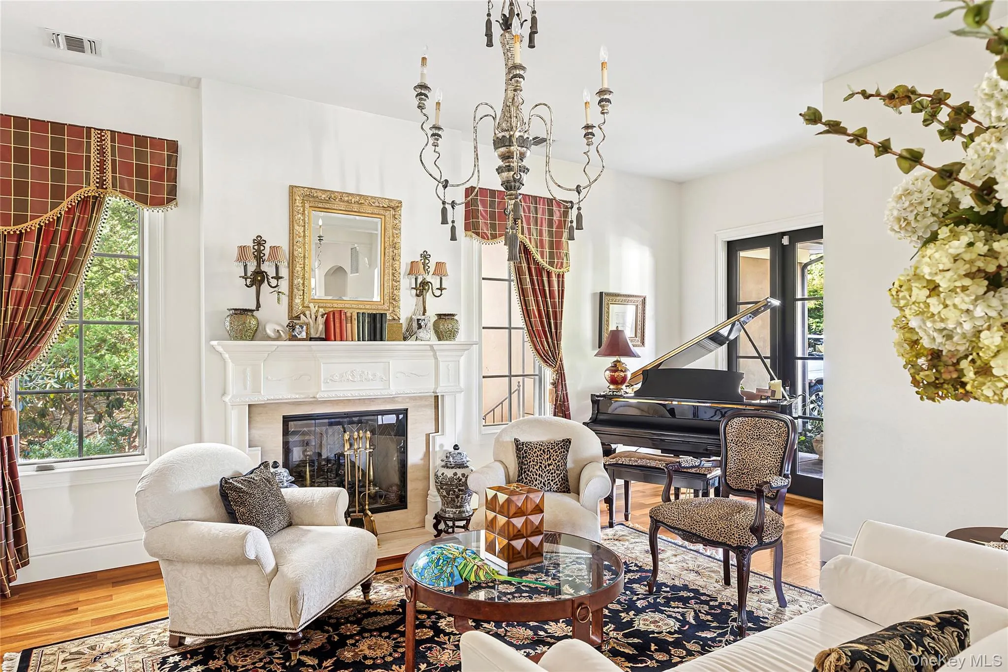 Sitting room featuring wood finished floors, a premium fireplace, a chandelier, and french doors Sitting room featuring wood finished floors, a premium fireplace, a chandelier, and french doors