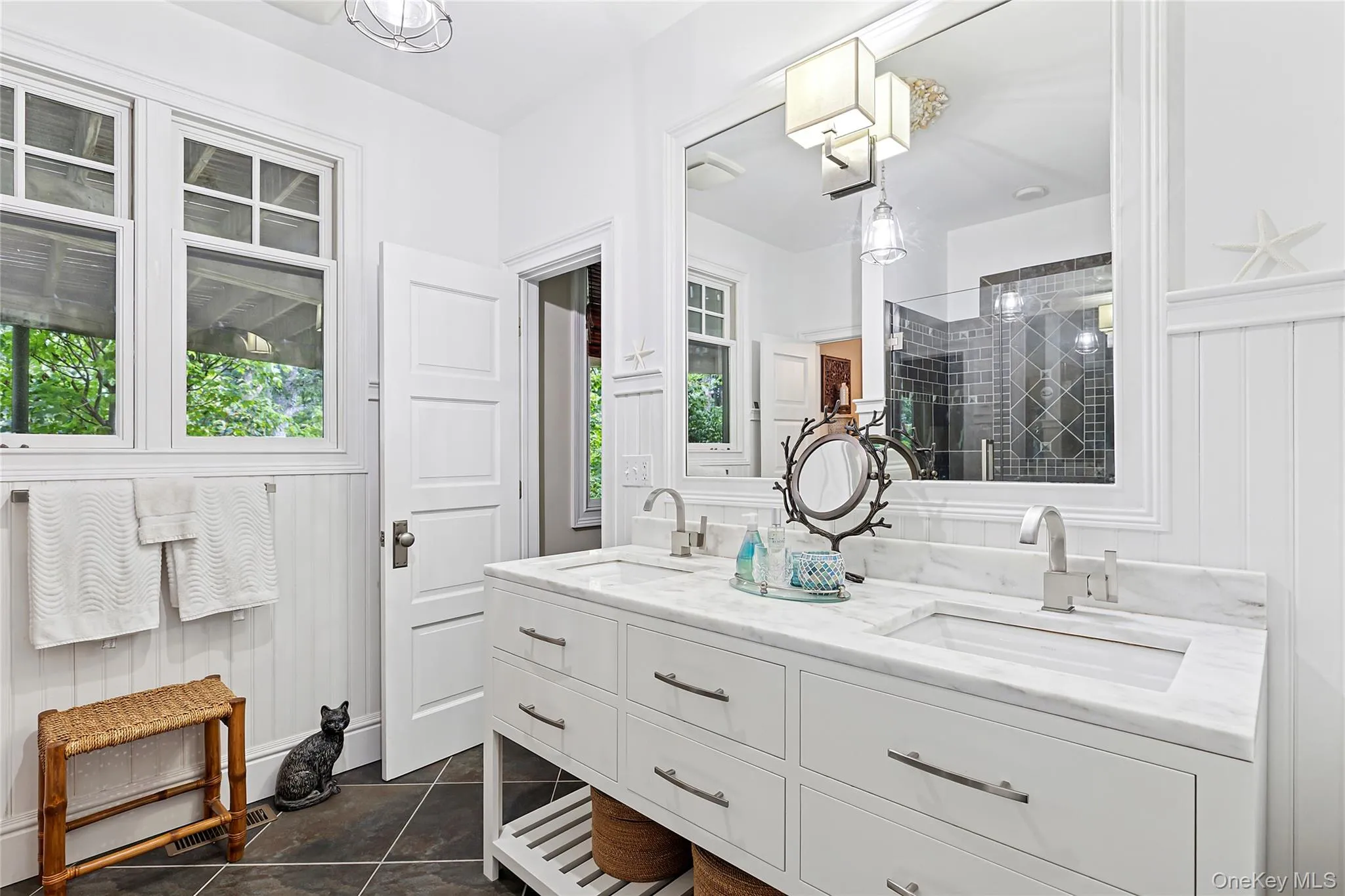 Bathroom with double vanity, a shower stall, and dark tile patterned floors Bathroom with double vanity, a shower stall, and dark tile patterned floors
