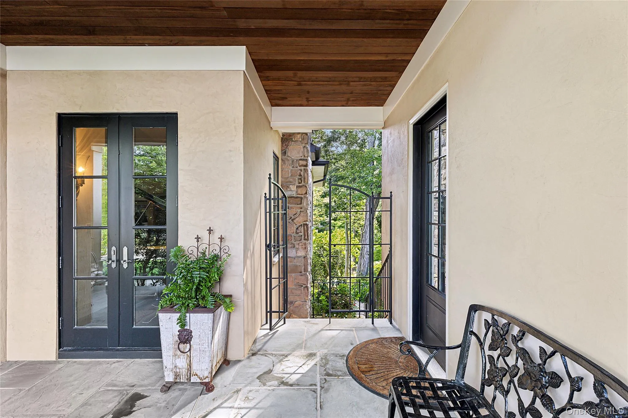 View of exterior entry featuring french doors, stucco siding, and a gate View of exterior entry featuring french doors, stucco siding, and a gate