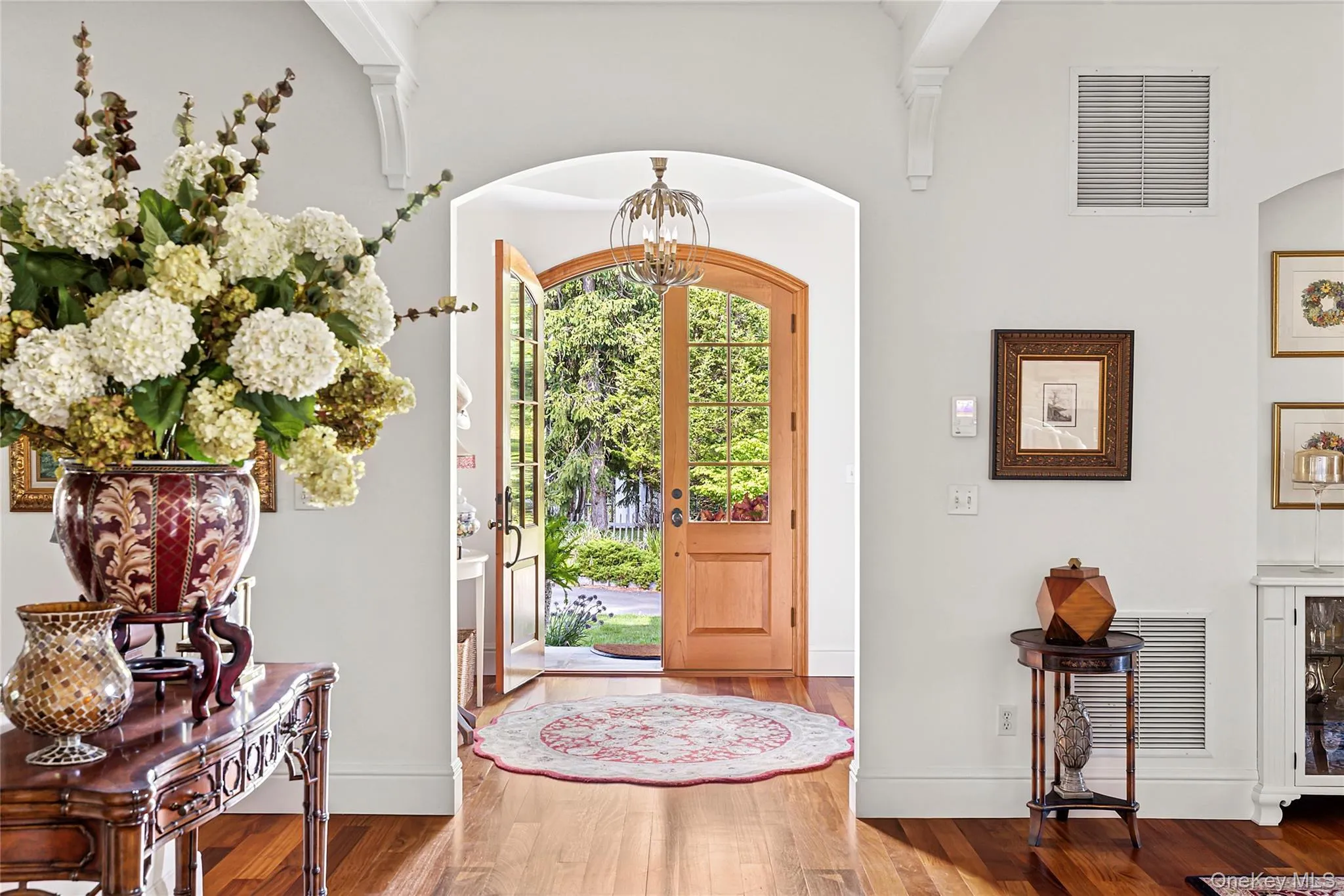 Foyer featuring wood finished floors, a chandelier, and arched walkways Foyer featuring wood finished floors, a chandelier, and arched walkways