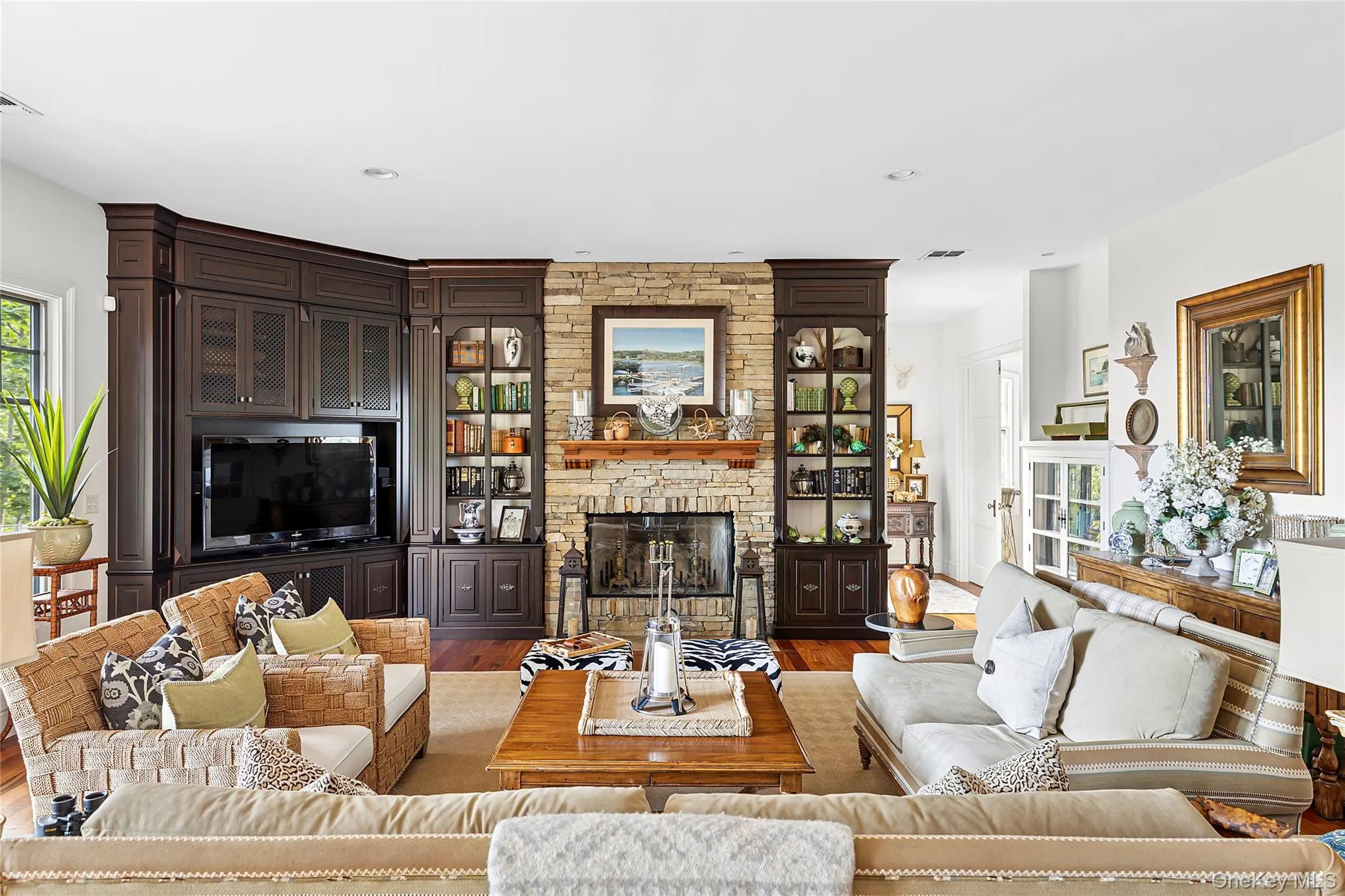 Living area featuring wood finished floors, a stone fireplace, and recessed lighting Living area featuring wood finished floors, a stone fireplace, and recessed lighting