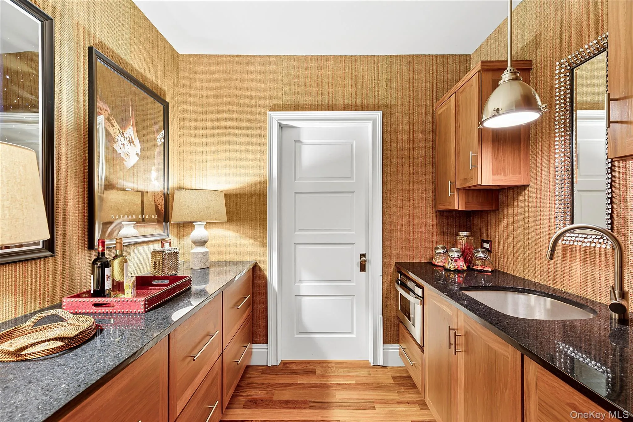 Kitchen featuring dark stone countertops, light wood-style flooring, hanging light fixtures, oven, and brown cabinetry Kitchen featuring dark stone countertops, light wood-style flooring, hanging light fixtures, oven, and brown cabinetry