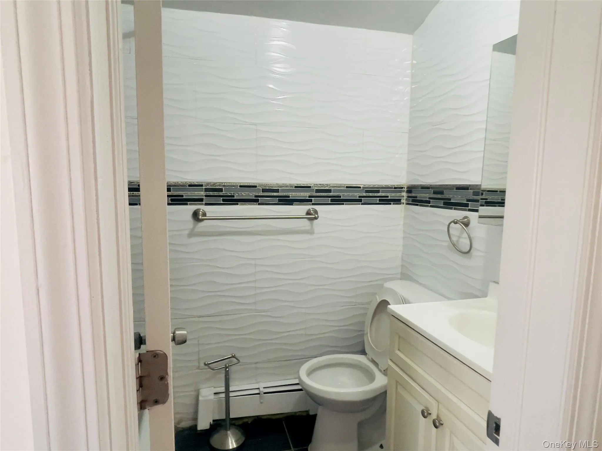 Bathroom featuring tile walls, baseboard heating, and vanity Bathroom featuring tile walls, baseboard heating, and vanity