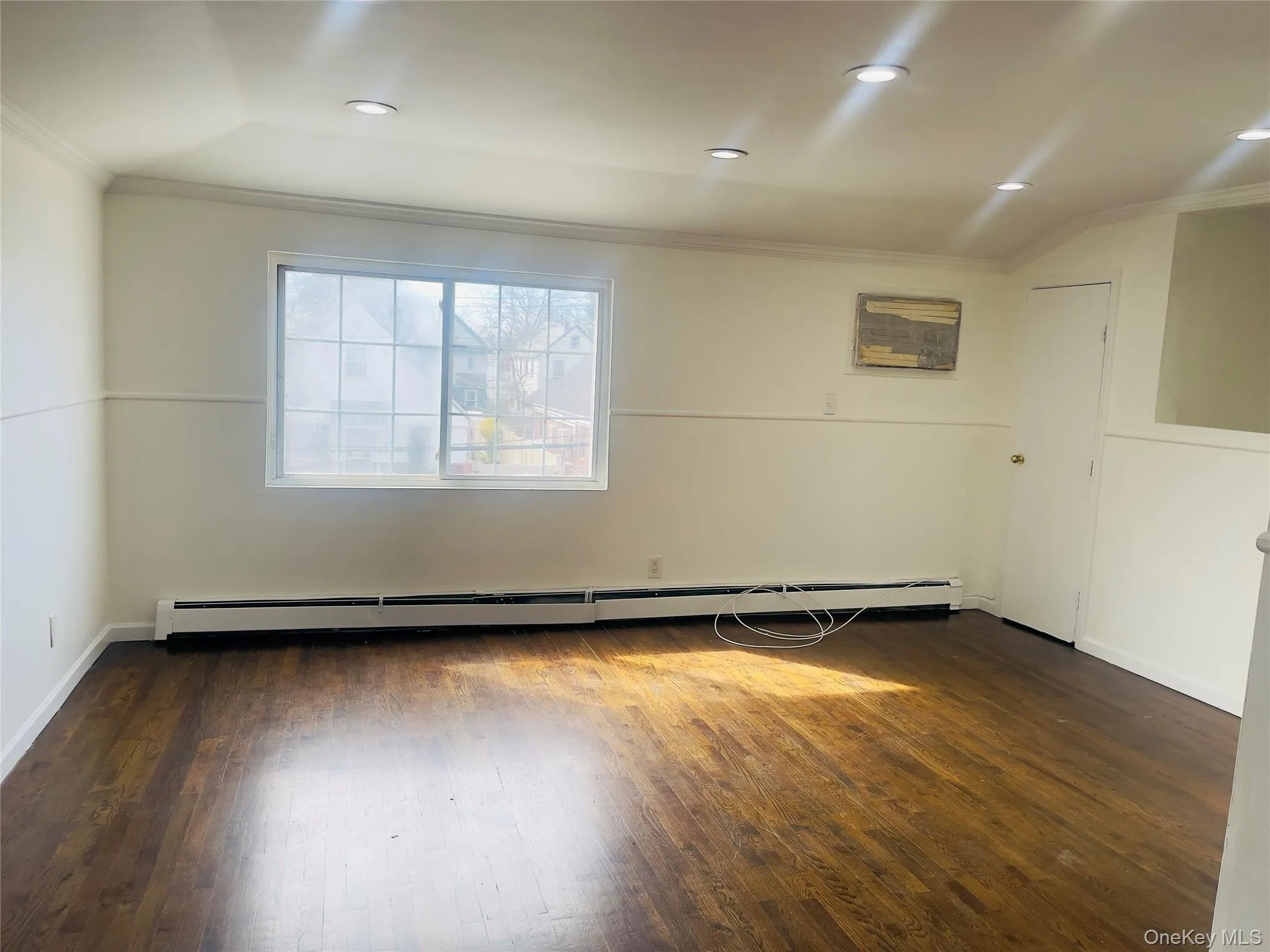 Unfurnished room featuring ornamental molding, dark wood finished floors, recessed lighting, and a baseboard radiator Unfurnished room featuring ornamental molding, dark wood finished floors, recessed lighting, and a baseboard radiator