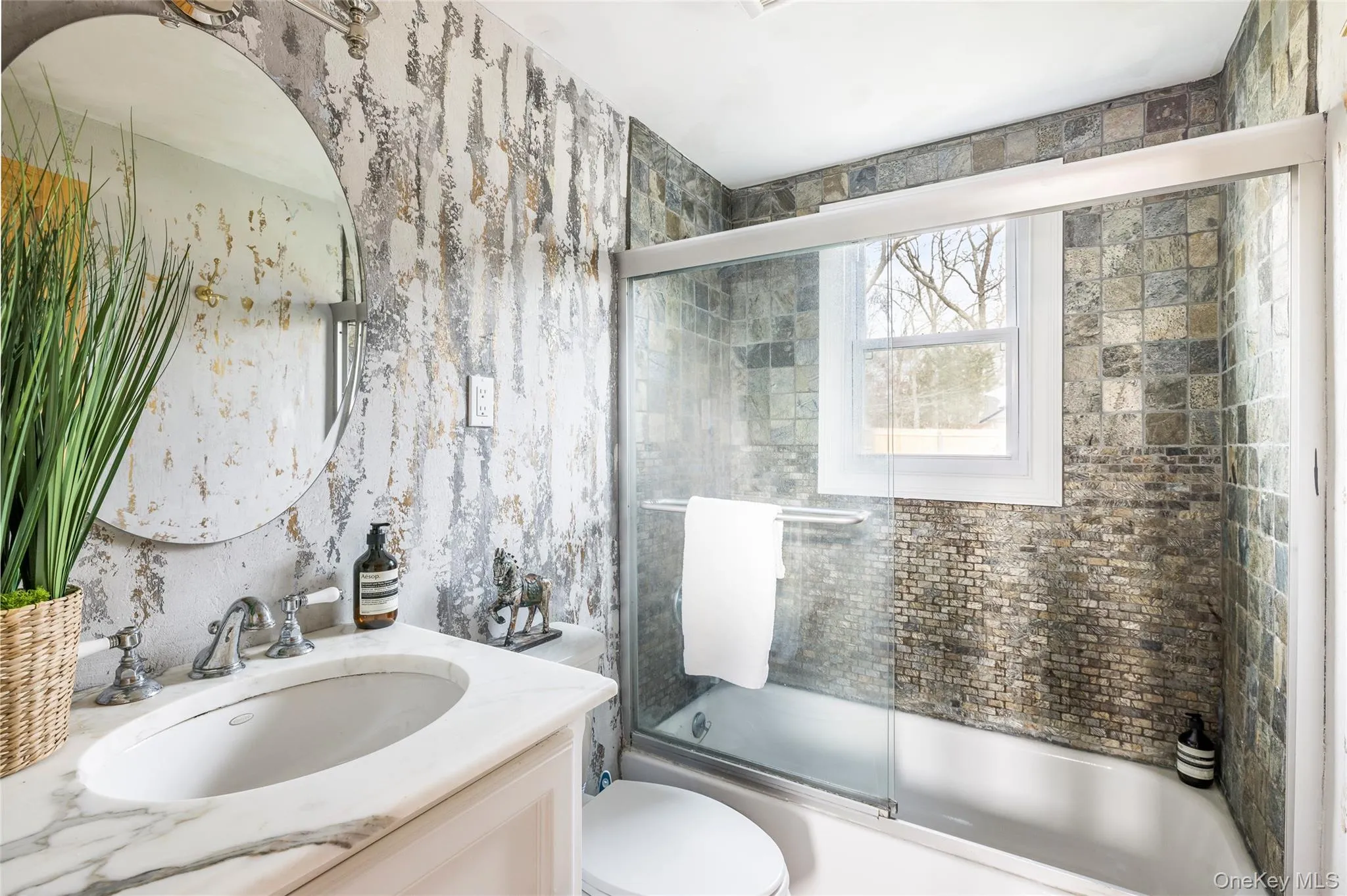 Full bath with wallpapered walls, shower / bath combination with glass door, and vanity Full bath with wallpapered walls, shower / bath combination with glass door, and vanity