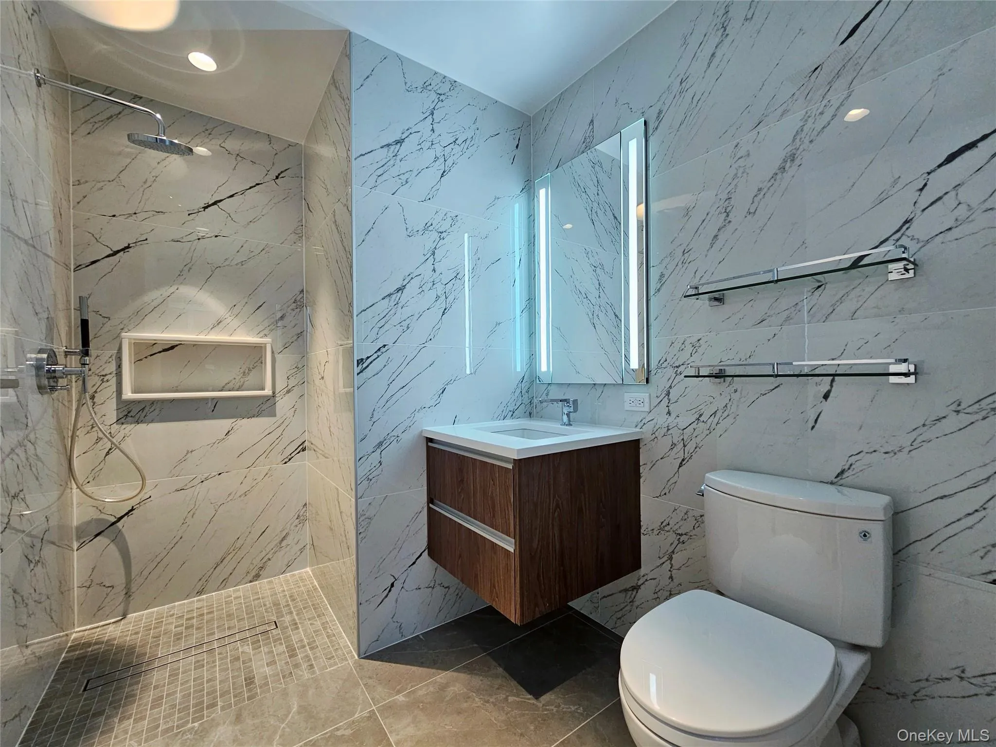 Bathroom featuring vanity, a marble finish shower, tile walls, and marble finish flooring Bathroom featuring vanity, a marble finish shower, tile walls, and marble finish flooring