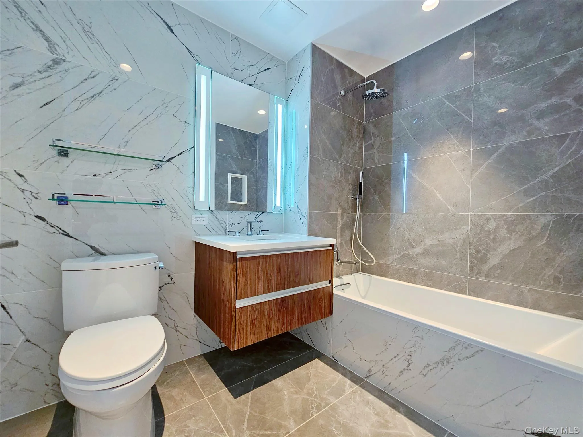 Bathroom with marble tiled flooring, vanity, a combined bath / shower with marble appearance, and tile walls Bathroom with marble tiled flooring, vanity, a combined bath / shower with marble appearance, and tile walls