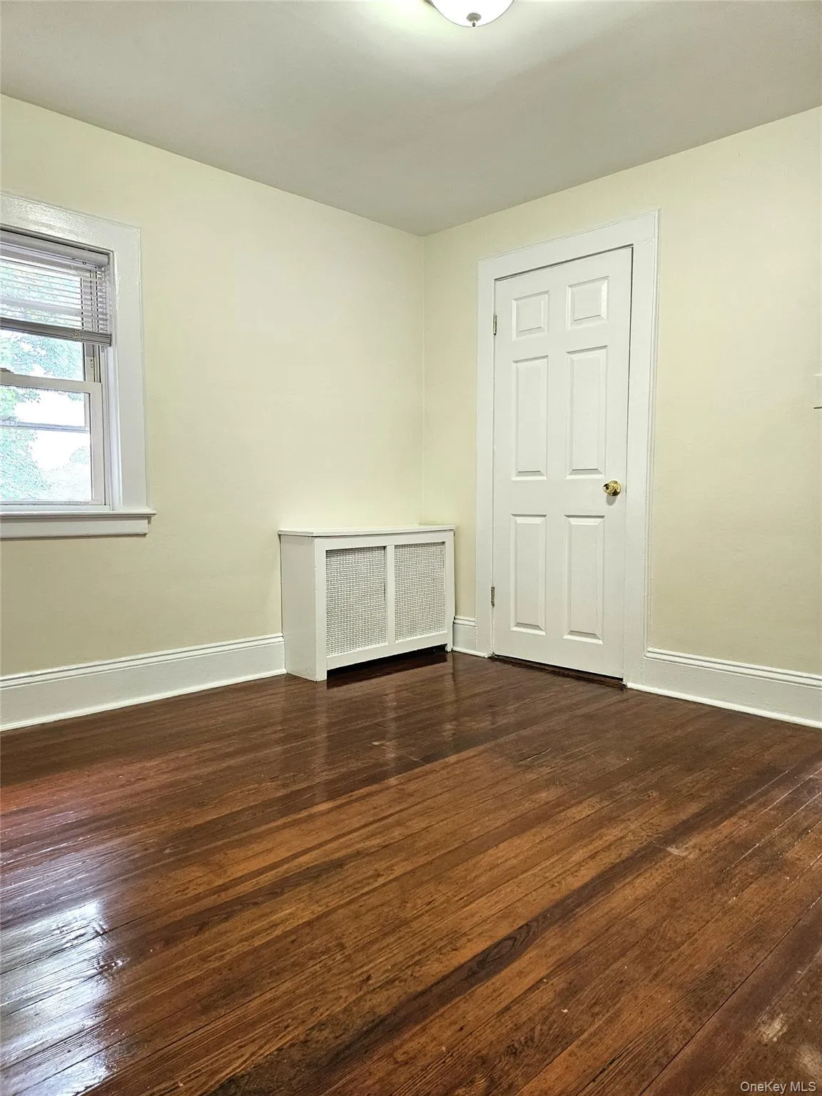 Spare room with radiator and dark wood finished floors Spare room with radiator and dark wood finished floors