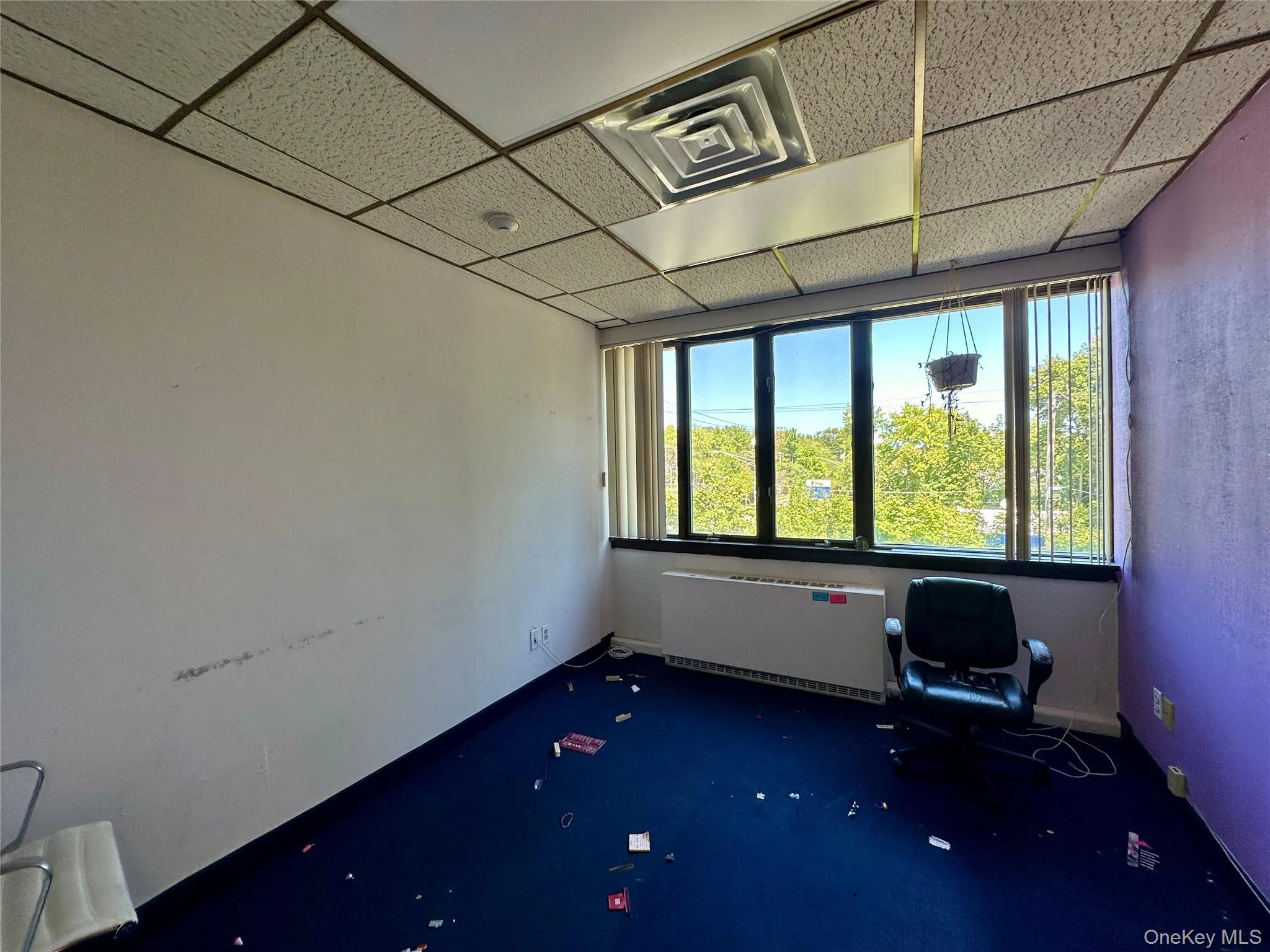 Unfurnished room with a drop ceiling and radiator heating unit Unfurnished room with a drop ceiling and radiator heating unit