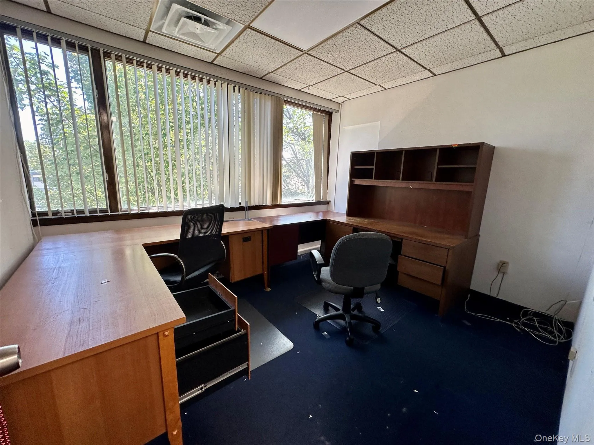 Office with a paneled ceiling and dark carpet Office with a paneled ceiling and dark carpet