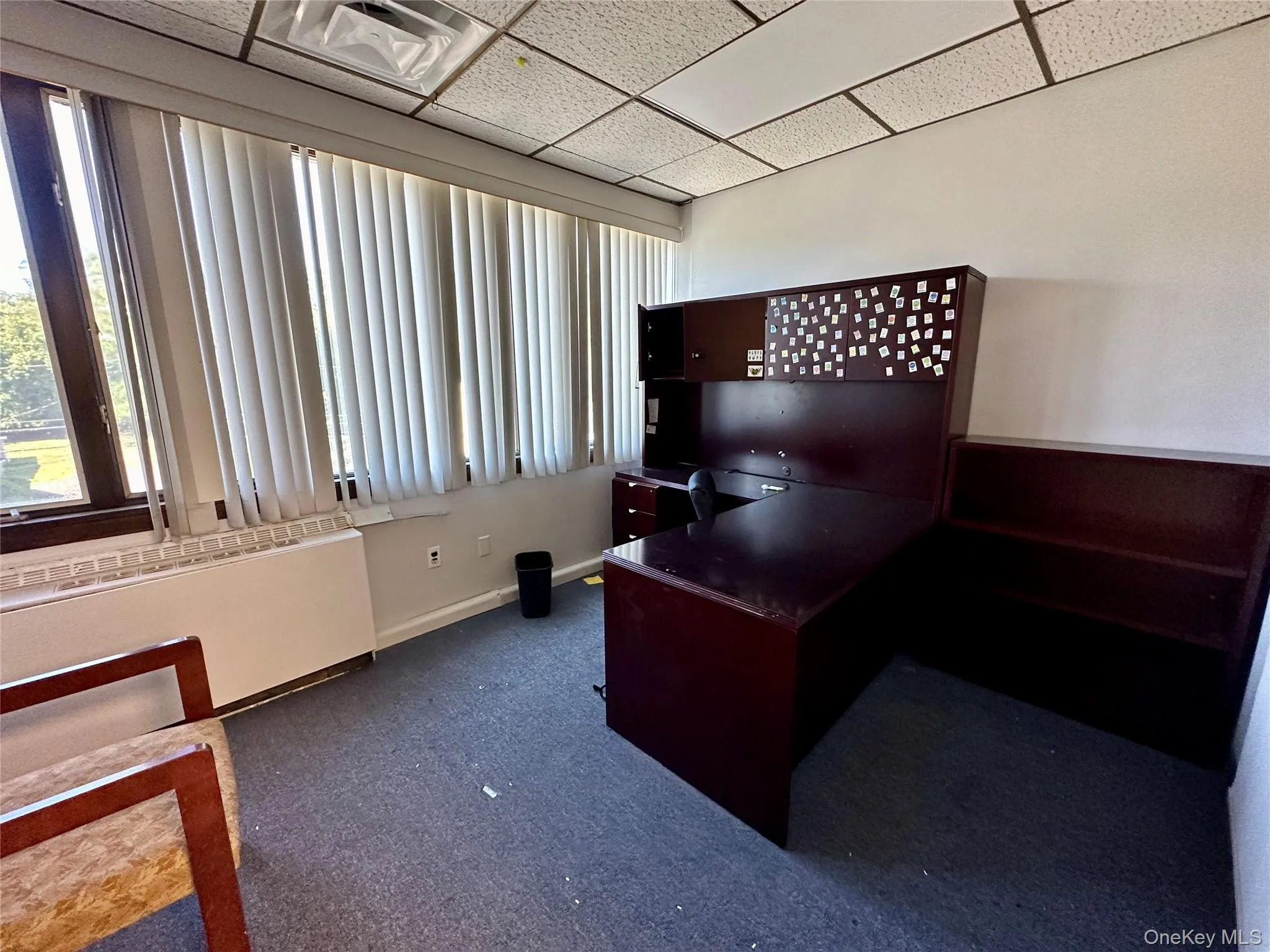 Office area featuring radiator, a drop ceiling, and dark carpet Office area featuring radiator, a drop ceiling, and dark carpet