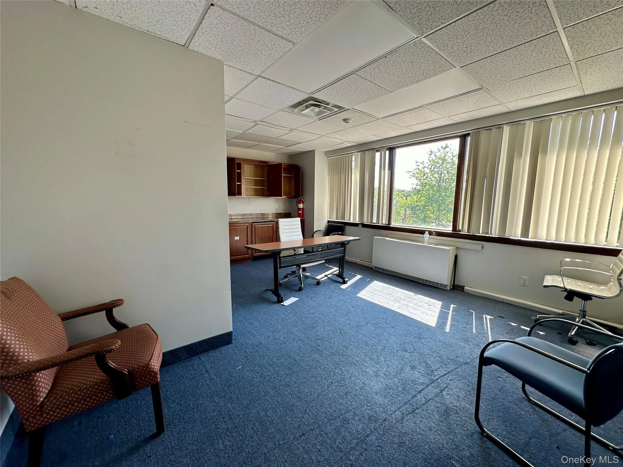 Office space featuring a drop ceiling and dark carpet Office space featuring a drop ceiling and dark carpet