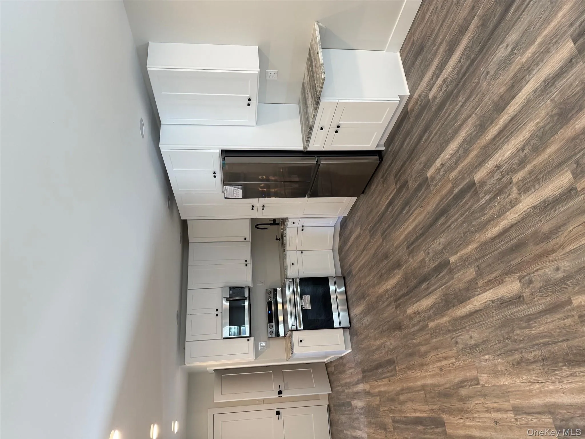 Kitchen featuring white cabinetry, stove, stainless steel fridge, dark wood-style flooring, and recessed lighting Kitchen featuring white cabinetry, stove, stainless steel fridge, dark wood-style flooring, and recessed lighting