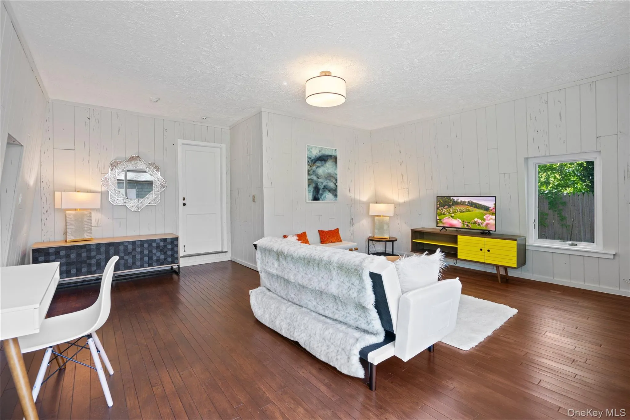 Living room with dark wood-style flooring, wooden walls, and a textured ceiling Living room with dark wood-style flooring, wooden walls, and a textured ceiling
