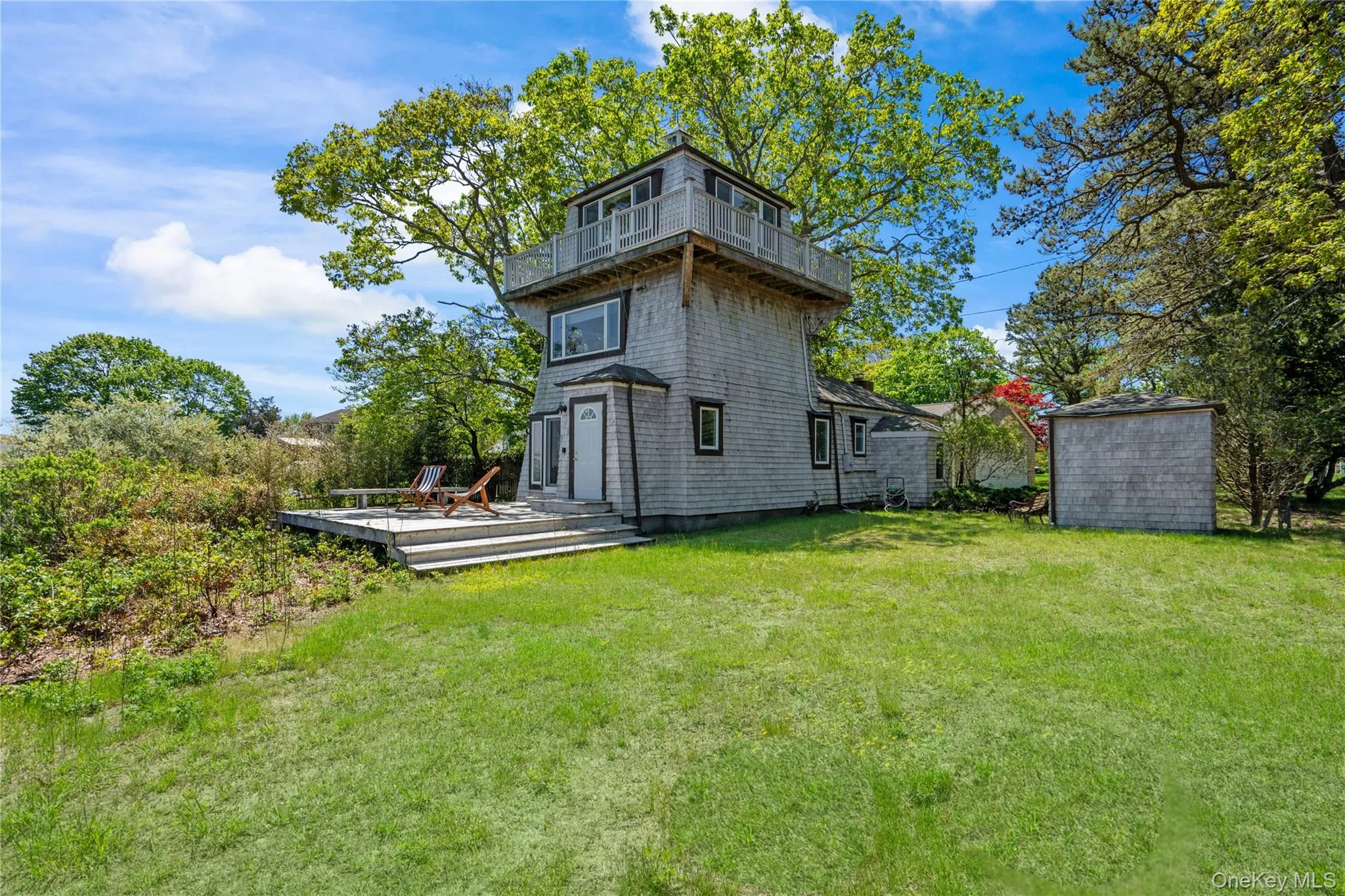 Back of property featuring a wooden deck, a lawn, a balcony, and an outdoor structure Back of property featuring a wooden deck, a lawn, a balcony, and an outdoor structure
