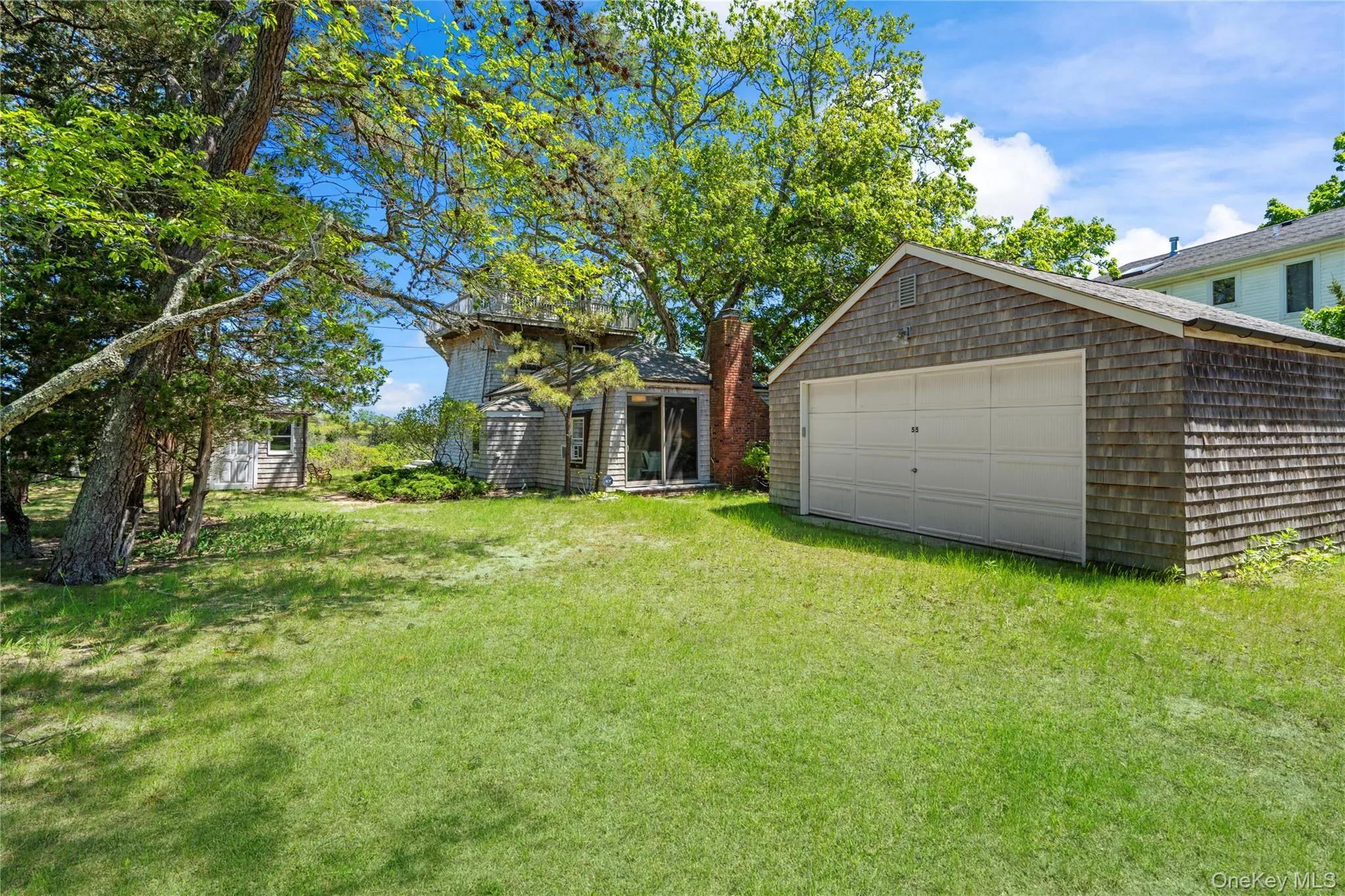 View of grassy yard featuring an outdoor structure and a detached garage View of grassy yard featuring an outdoor structure and a detached garage