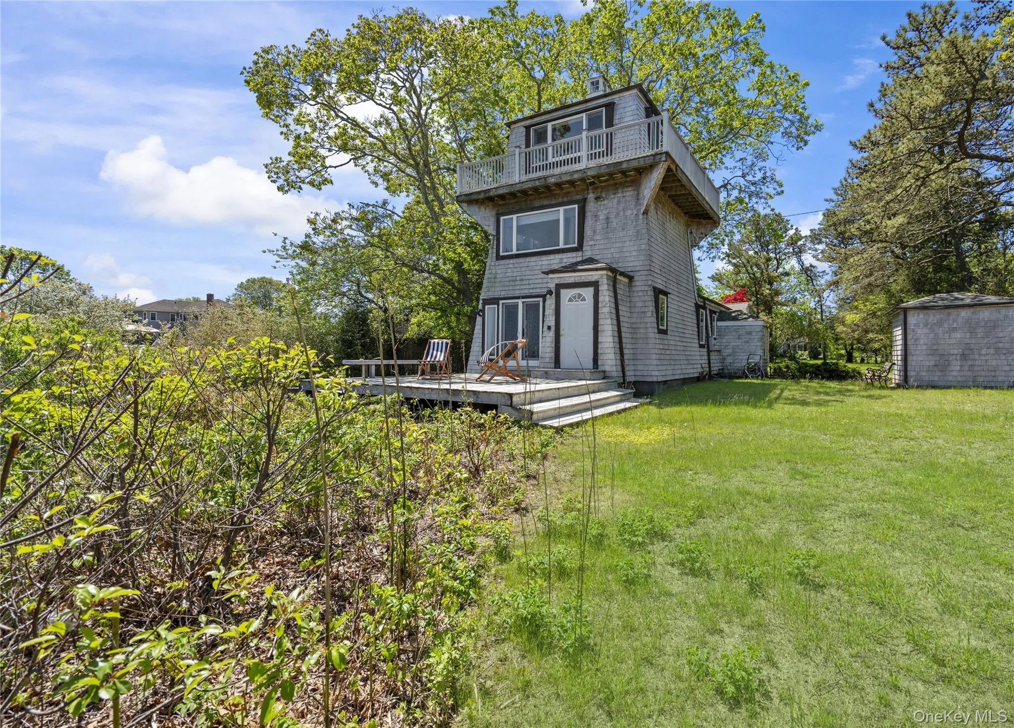 Back of house with a wooden deck, a balcony, a lawn, and a storage shed Back of house with a wooden deck, a balcony, a lawn, and a storage shed