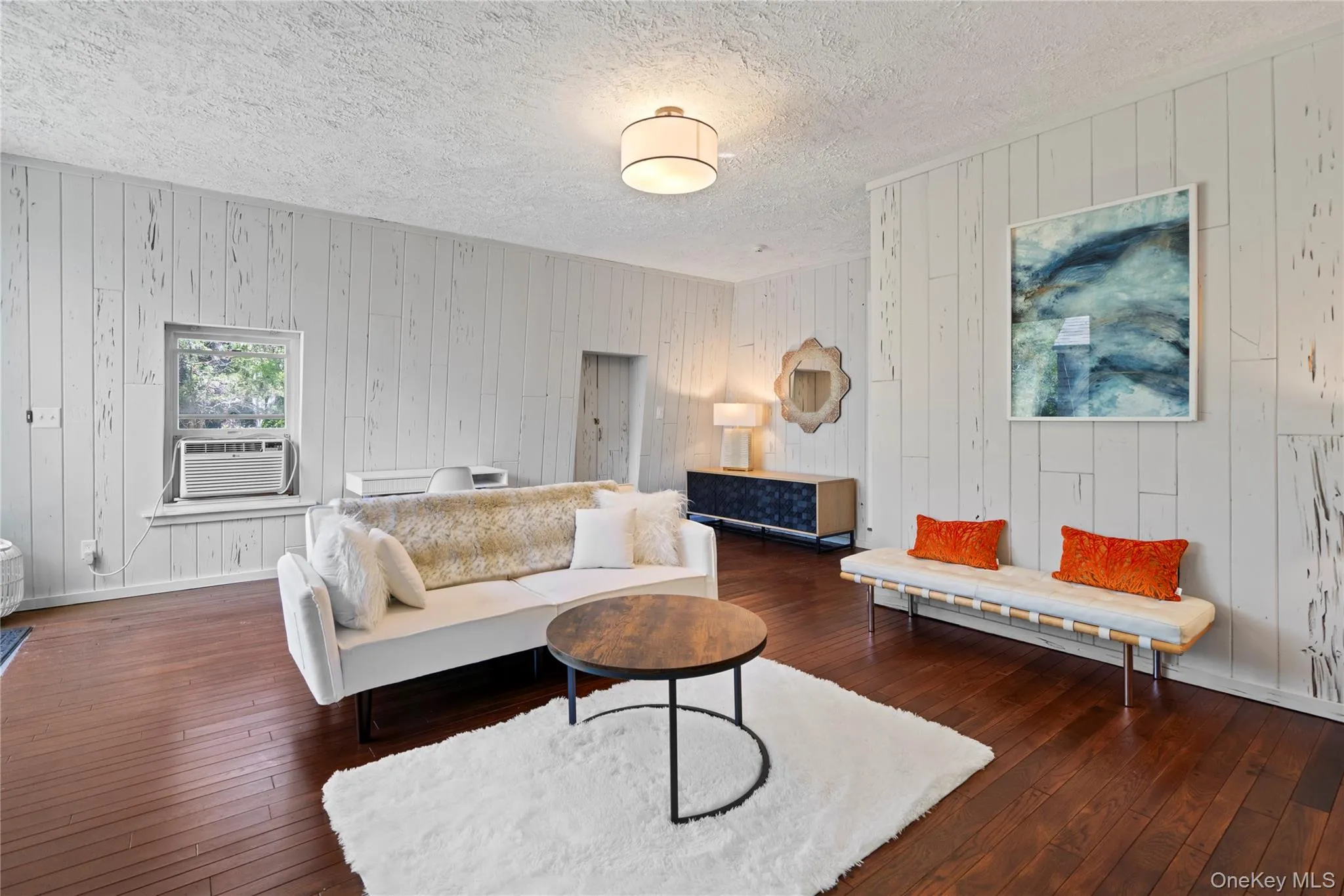 Living area featuring wood walls, dark wood finished floors, and a textured ceiling Living area featuring wood walls, dark wood finished floors, and a textured ceiling