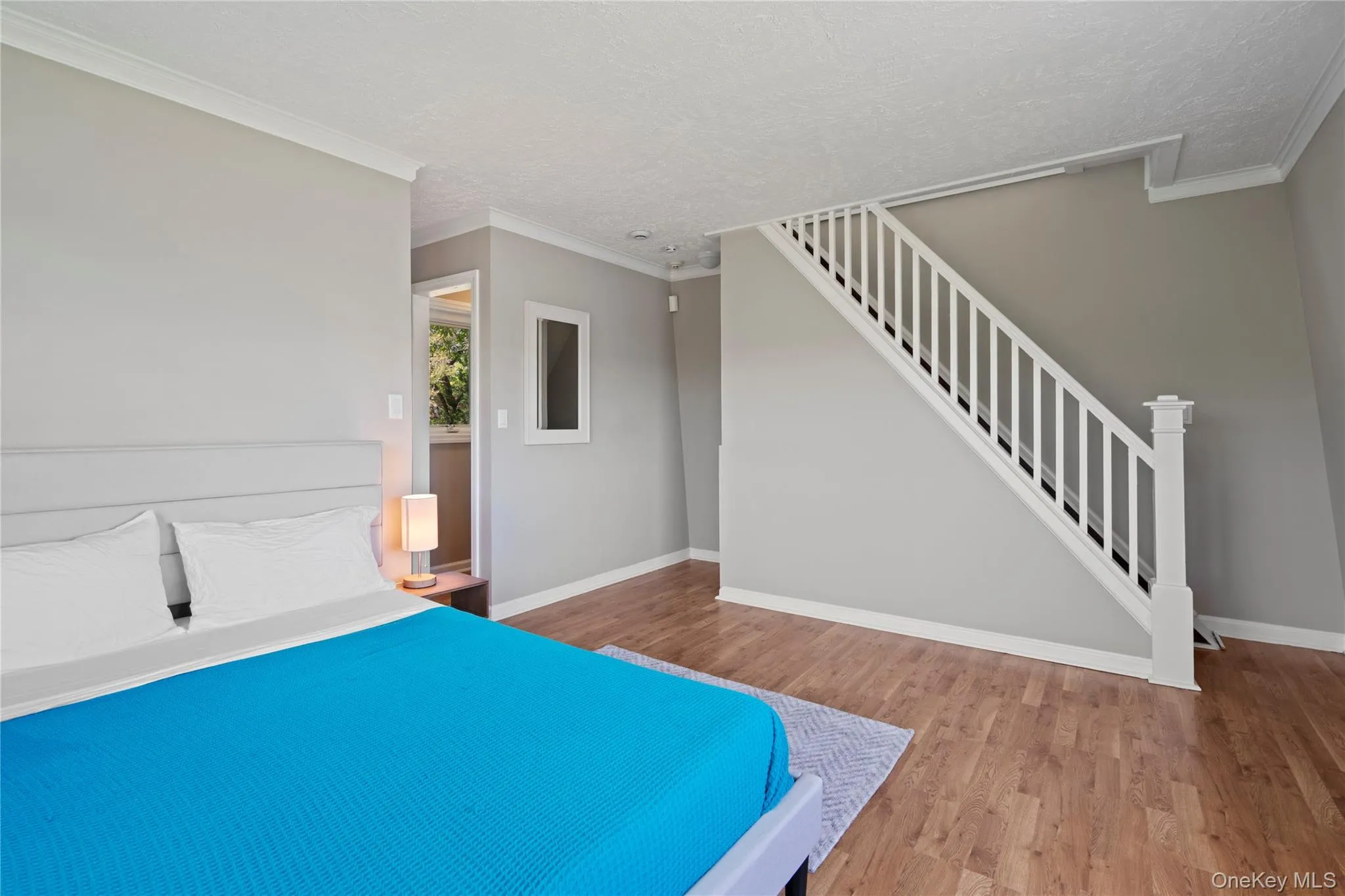 Unfurnished bedroom featuring crown molding, light wood-style floors, and a textured ceiling Unfurnished bedroom featuring crown molding, light wood-style floors, and a textured ceiling