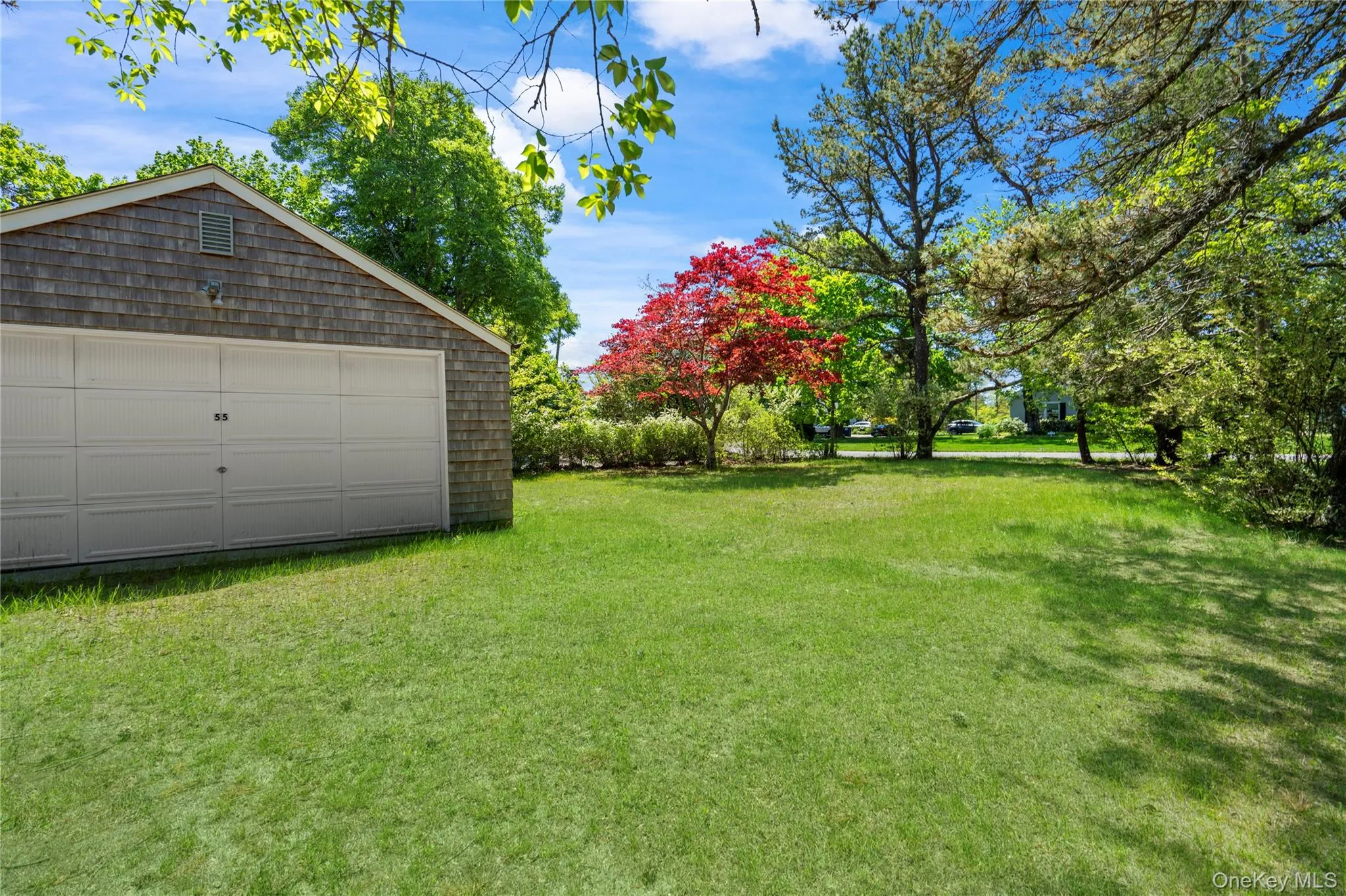 View of green lawn featuring an outbuilding and a detached garage View of green lawn featuring an outbuilding and a detached garage