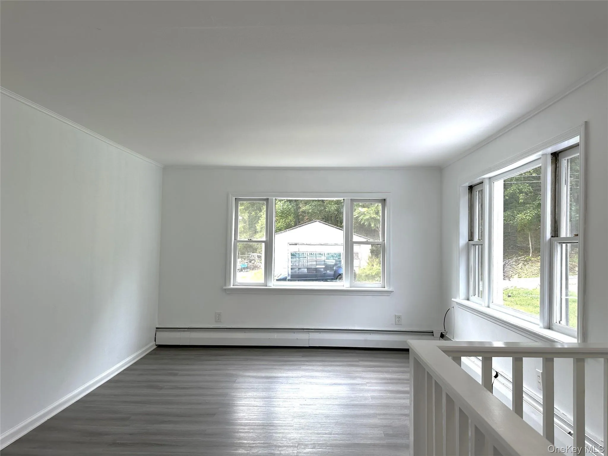 Spare room with wood finished floors, a baseboard heating unit, and crown molding Spare room with wood finished floors, a baseboard heating unit, and crown molding